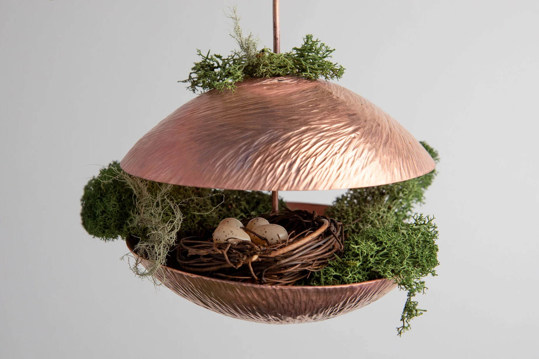 Decorative hanging lamp designed to look like a mushroom, with a metallic pinkish cap, surrounded by moss and small eggs in a nest.