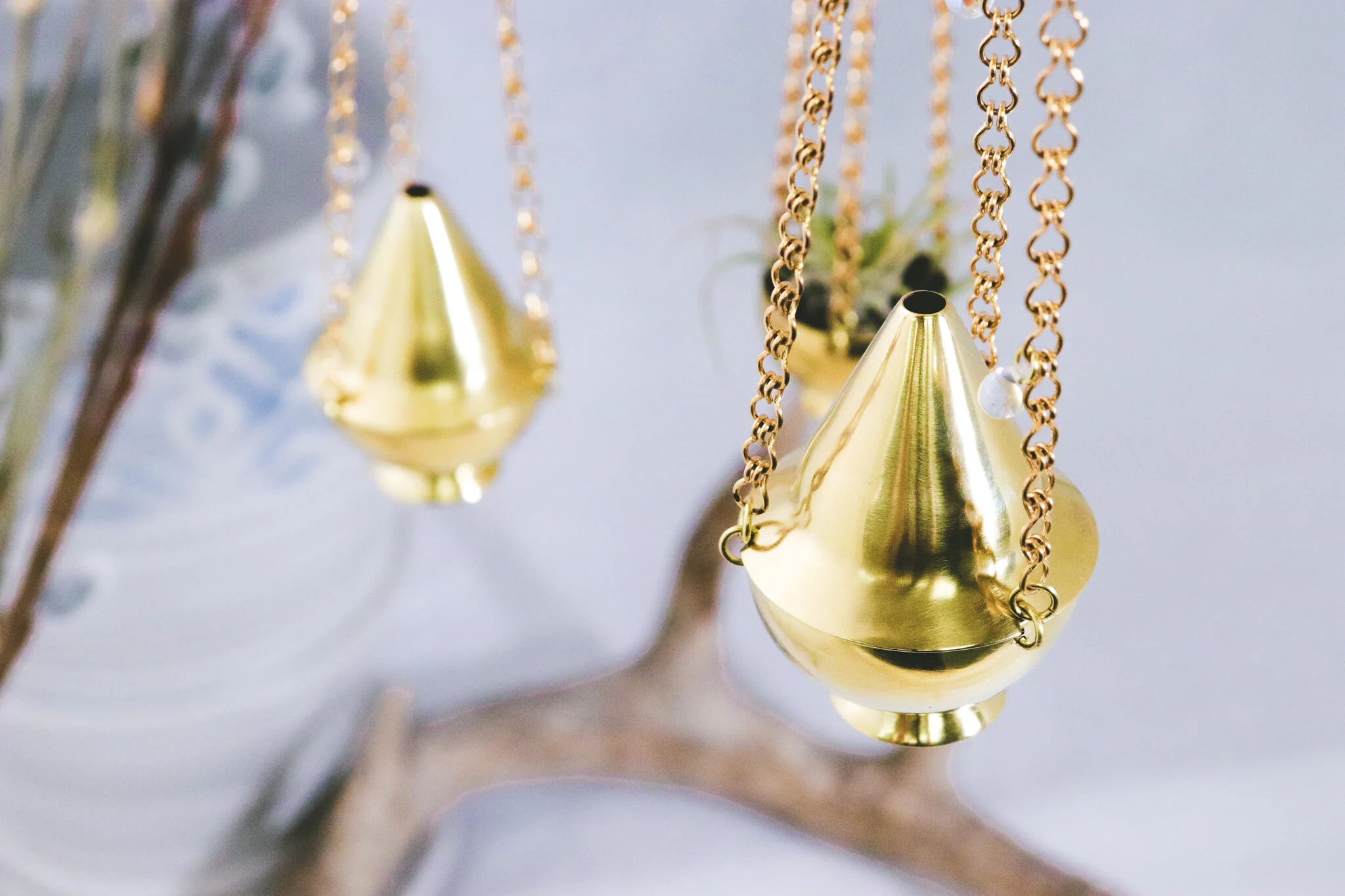 Close-up of gold cone-shaped ornaments hanging from chains on a Christmas tree.