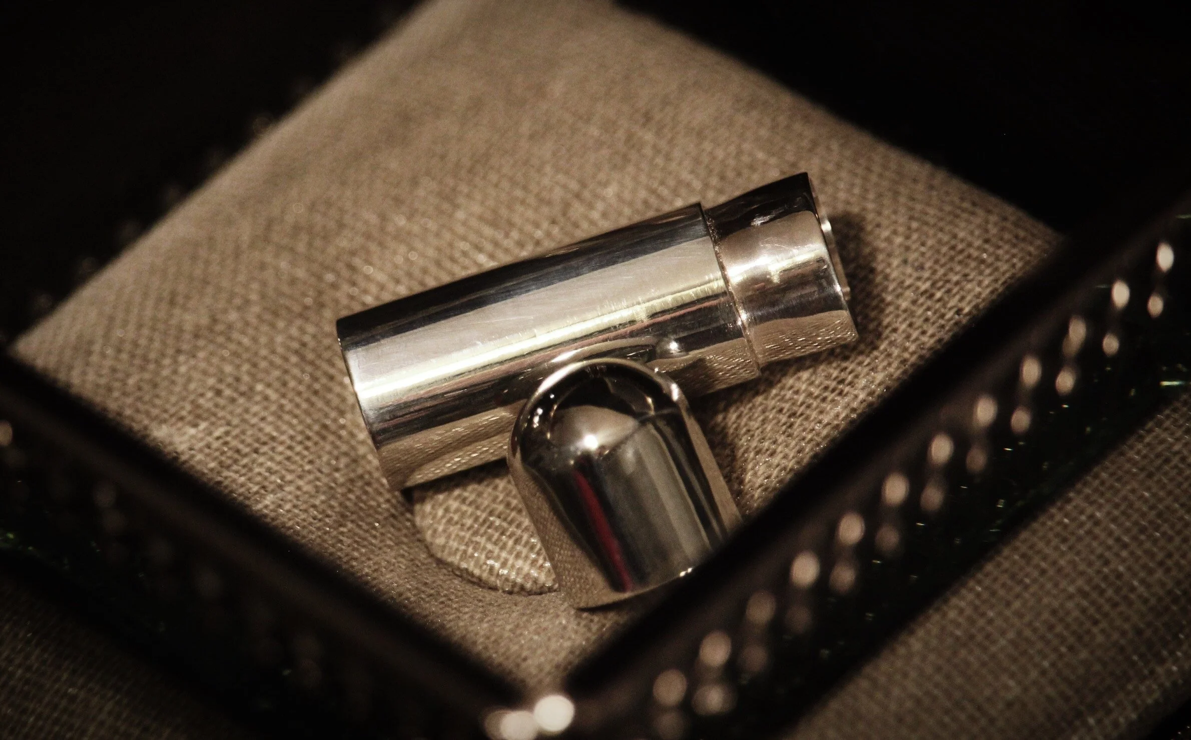 A shiny metallic lipstick holder inside a black box with foam padding.