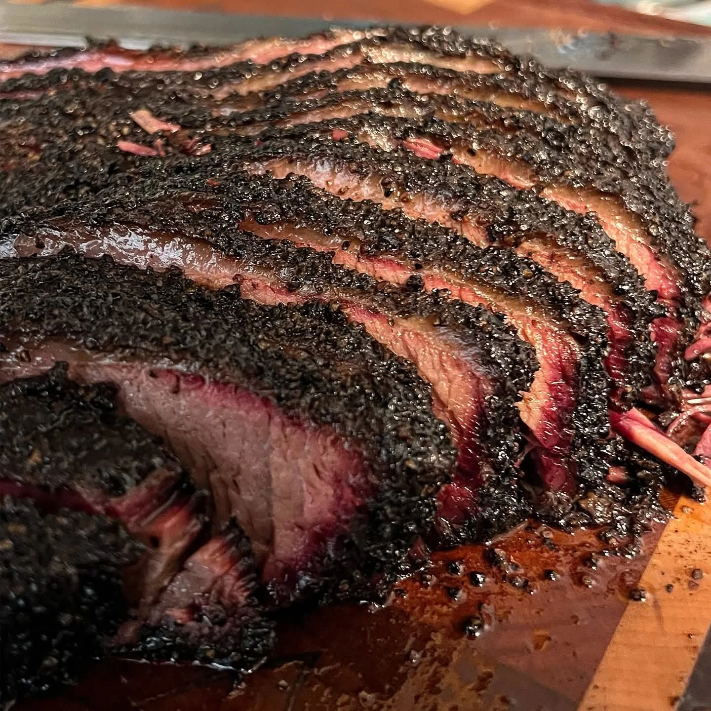 Juicy slices of Texas-style slow-smoked beef brisket with a rich smoky bark, prepared at Moo Moo Smokehouse & Grill in Auckland.