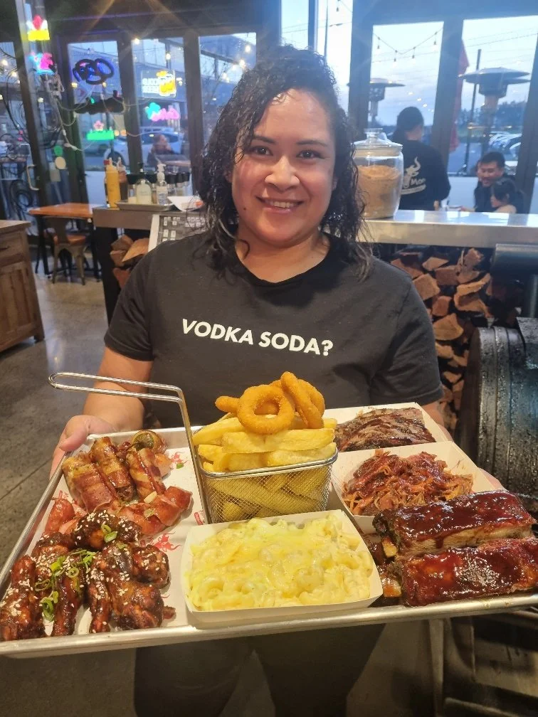 Moo Moo Smokehouse & Grill manager presenting the popular Moo Moo Ultimate BBQ Platter, loaded with smoked meats, fries, onion rings and mac and cheese.