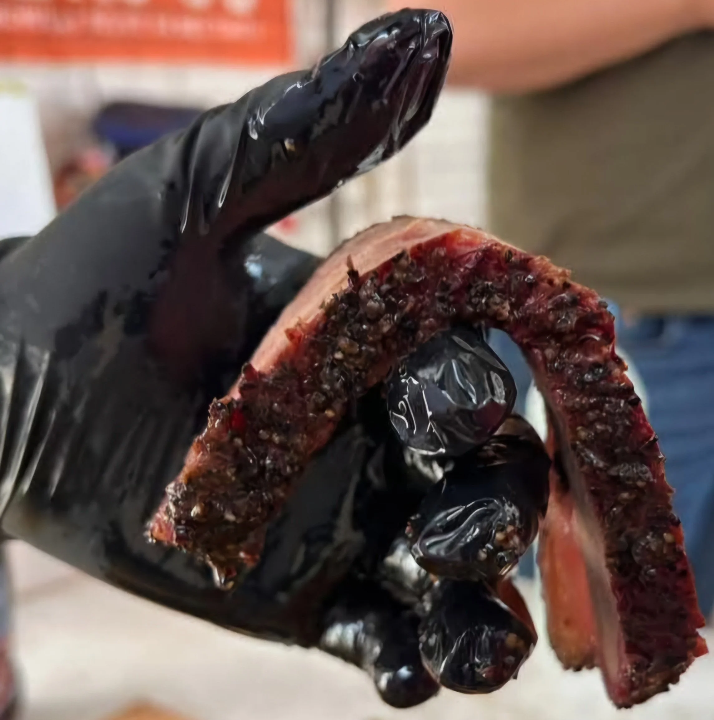 Moo Moo Smokehouse & Grill pitmaster demonstrating the tenderness of a sliced, slow-smoked beef brisket with rich Texas-style BBQ bark.