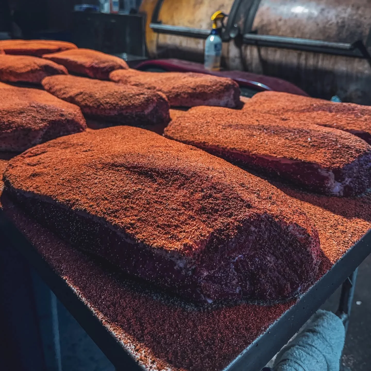 Raw beef brisket coated with a BBQ spice rub, ready for low-and-slow smoking at Moo Moo Smokehouse & Grill.