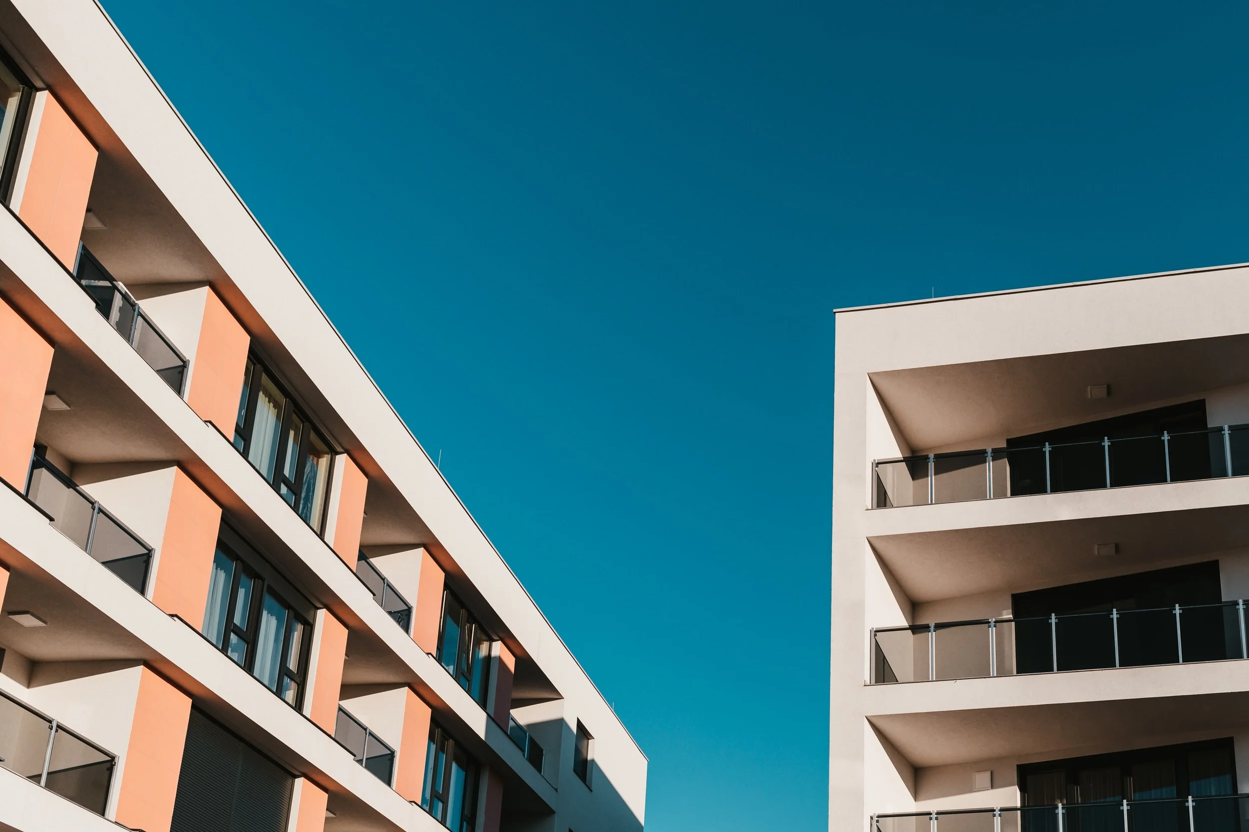 Modern apartment buildings with balconies against a clear blue sky.