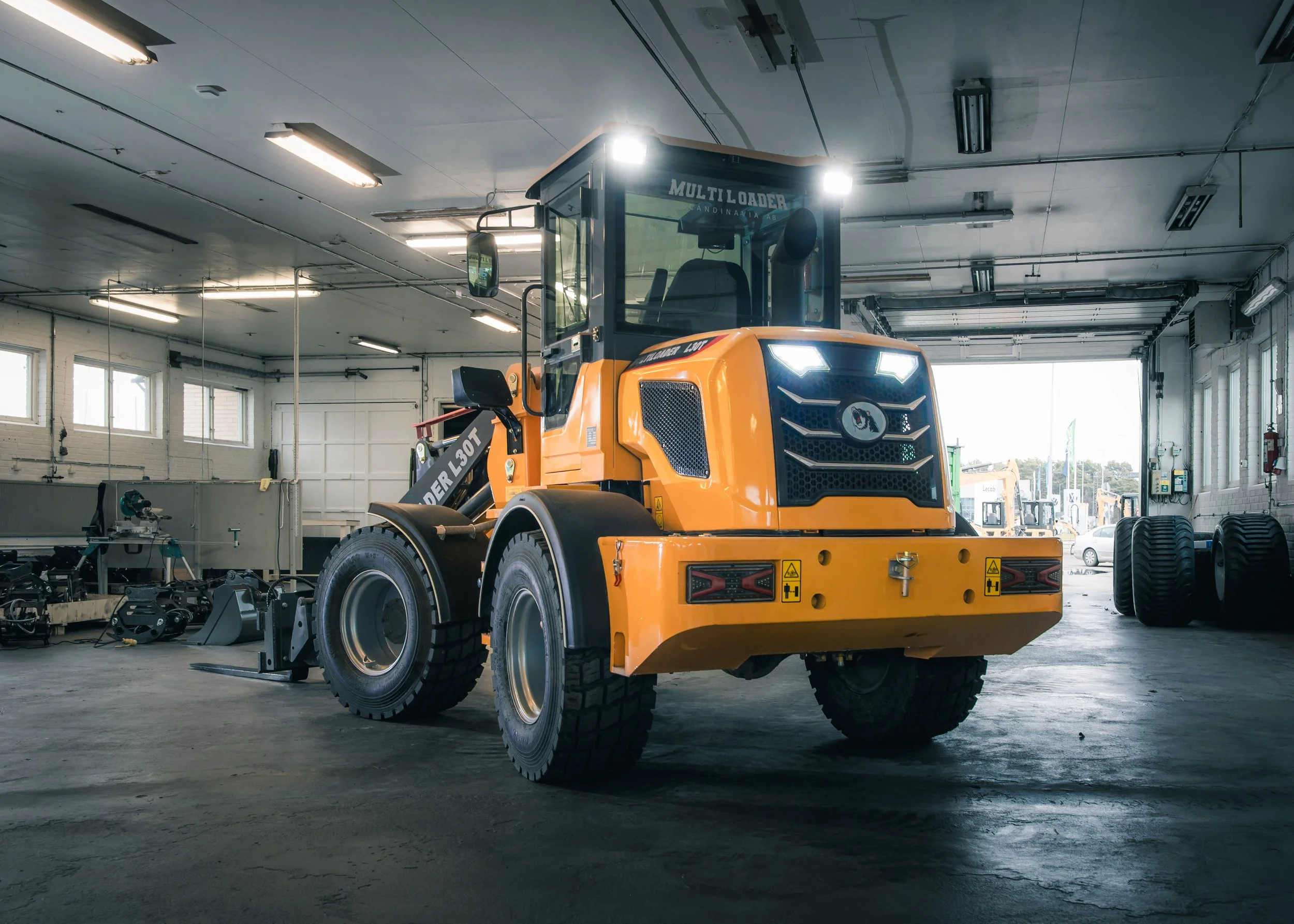 Yellow construction vehicle in a garage, with large tires and a black operator cabin.