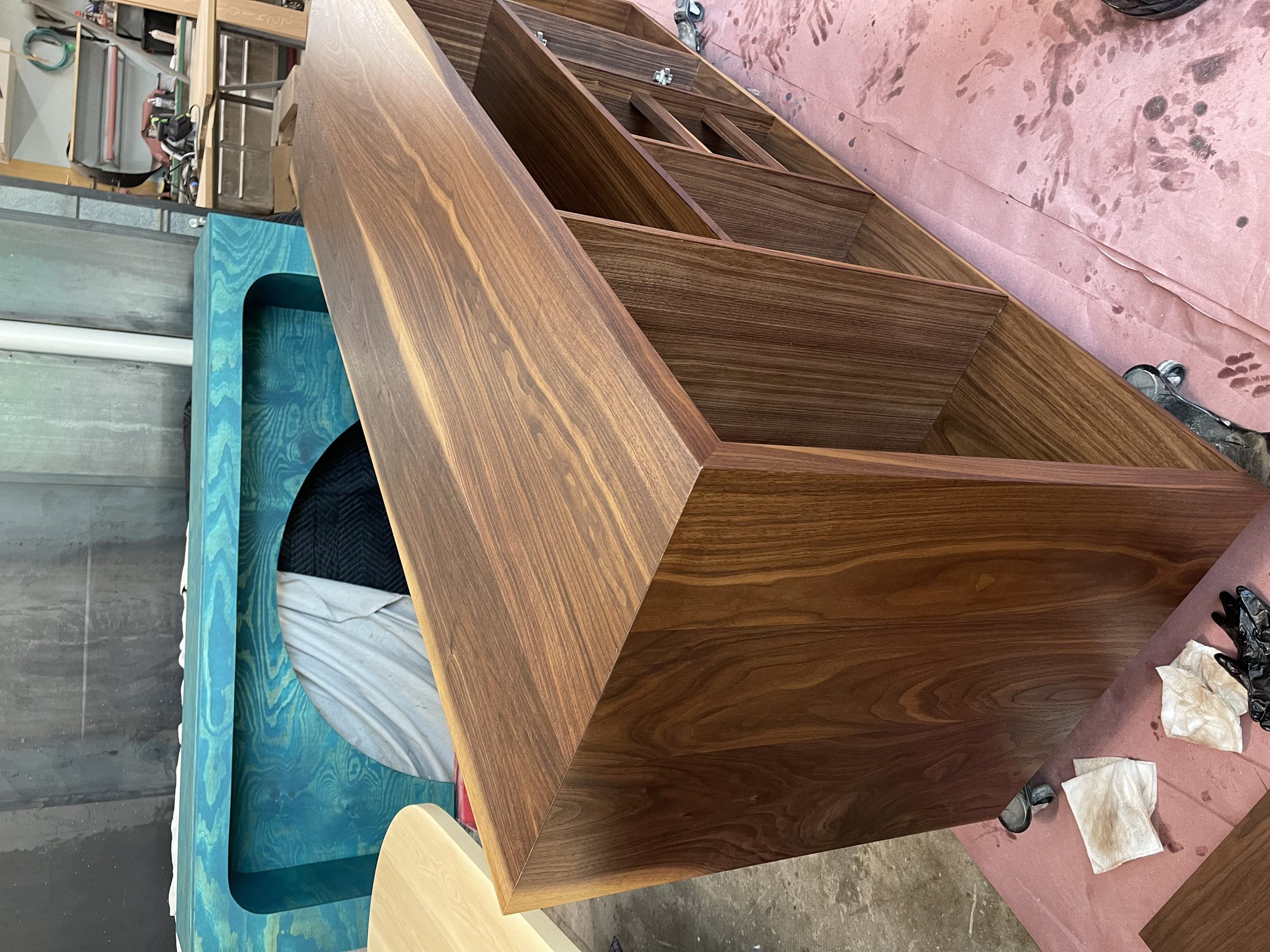 Wooden furniture piece with multiple shelves inside a workshop, surrounded by tools and materials.