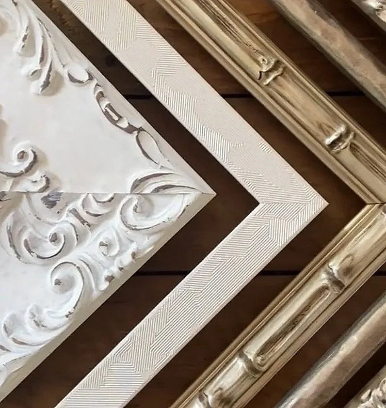 Close-up of decorative picture frames with ornate designs and metallic finishes, arranged on a wooden surface.