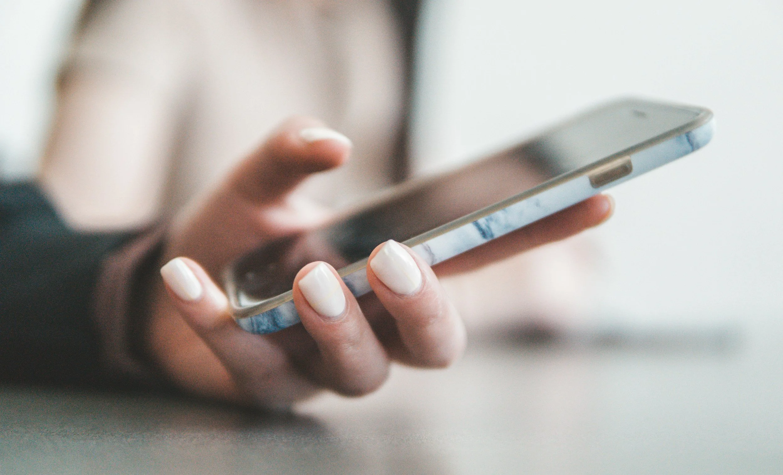 Close-up of a person's hand holding a smartphone with a marble-patterned case.