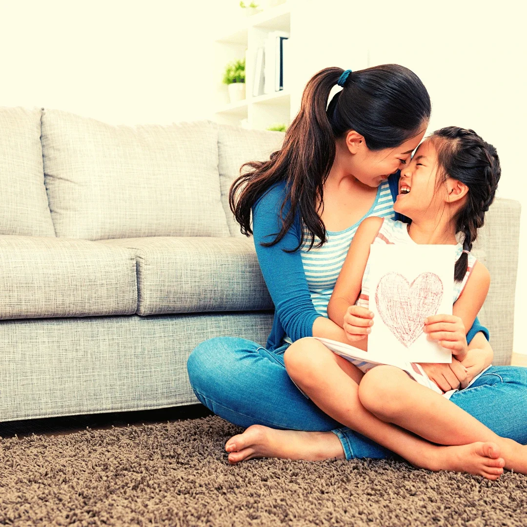 Mom and young daughter laughing together in a moment of connection.
