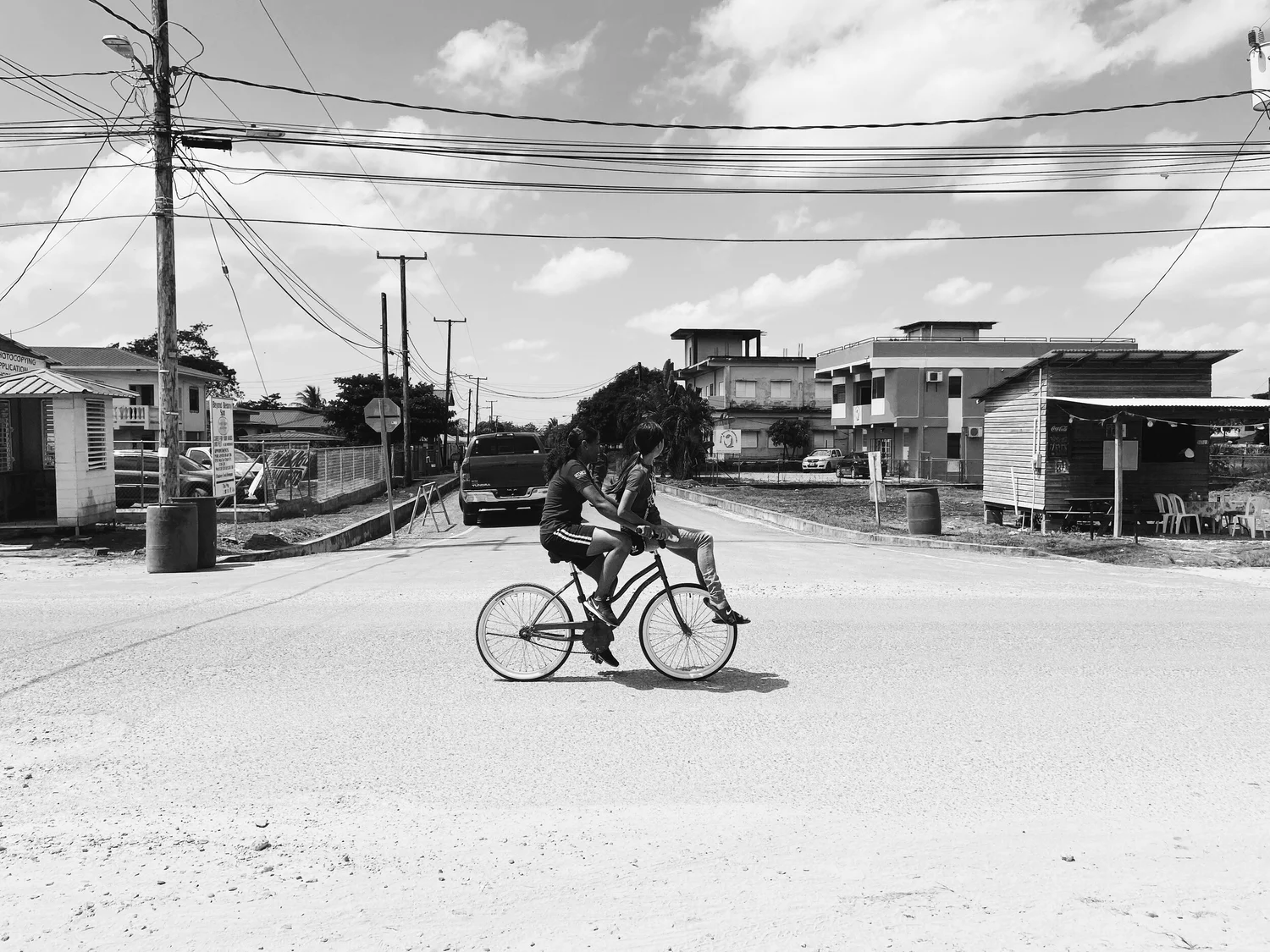 A person cycling down a wide street lined with low buildings.