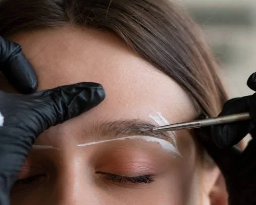 Licensed aesthetician shaping client's eyebrows with precision