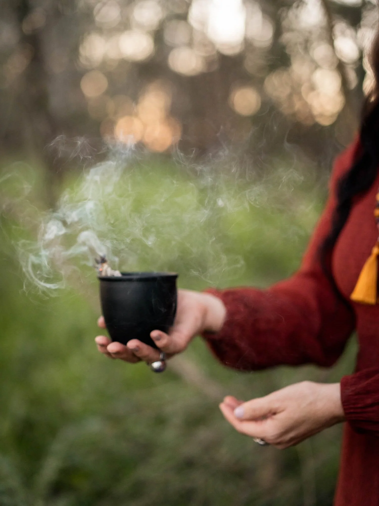 A woman burning sage in nature – image captured by Sunday Muse Studio