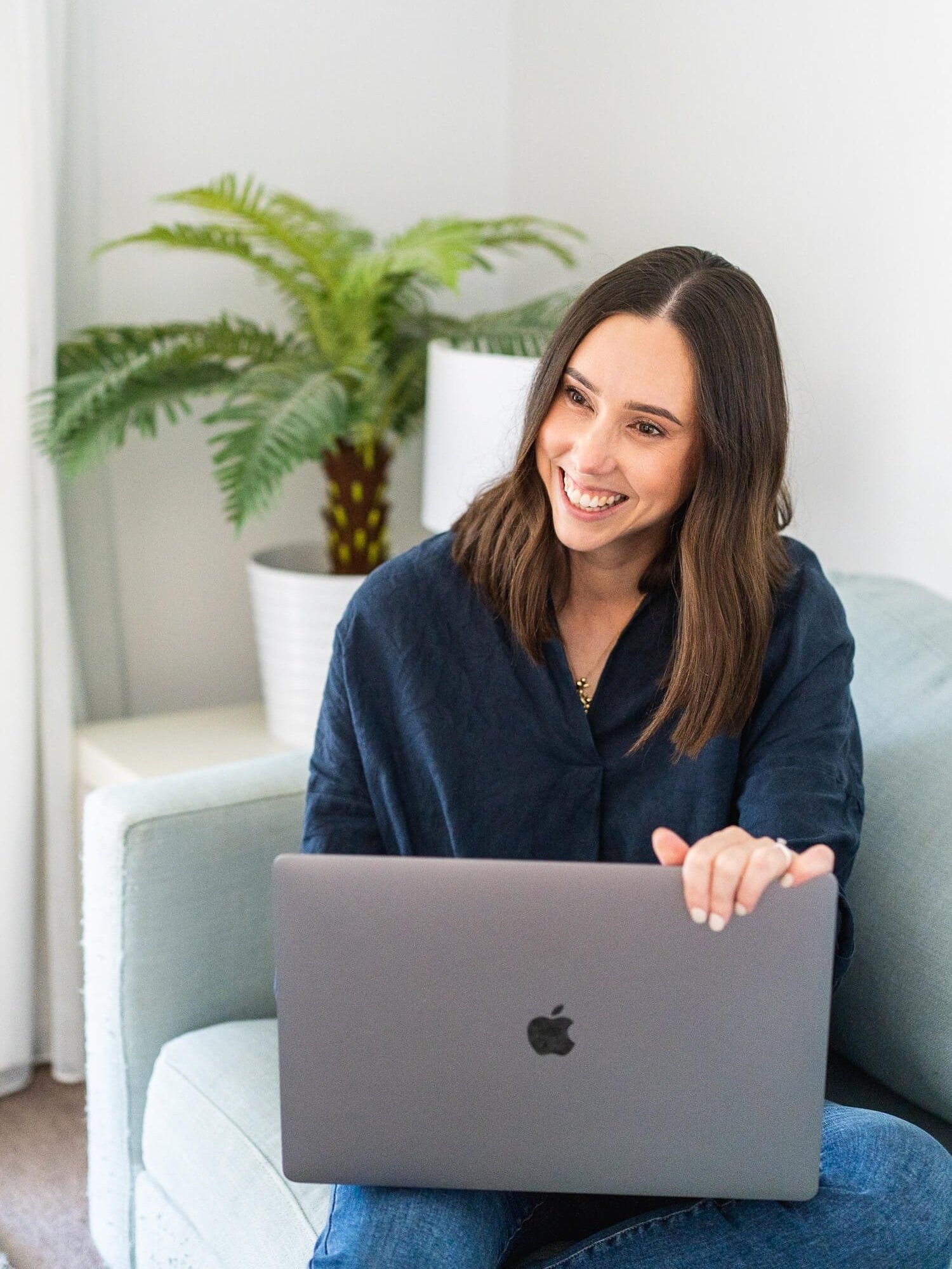 A web designer smiling happily as she creates on her laptop  – image captured by Sunday Muse Studio