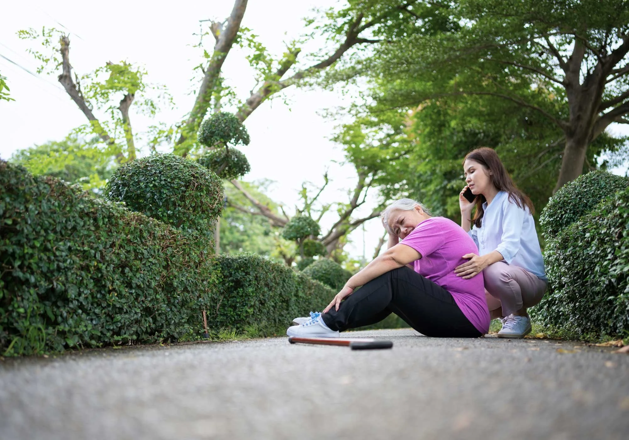 An old woman with a back injury after slipping and falling getting help from her daughter while sitting outside