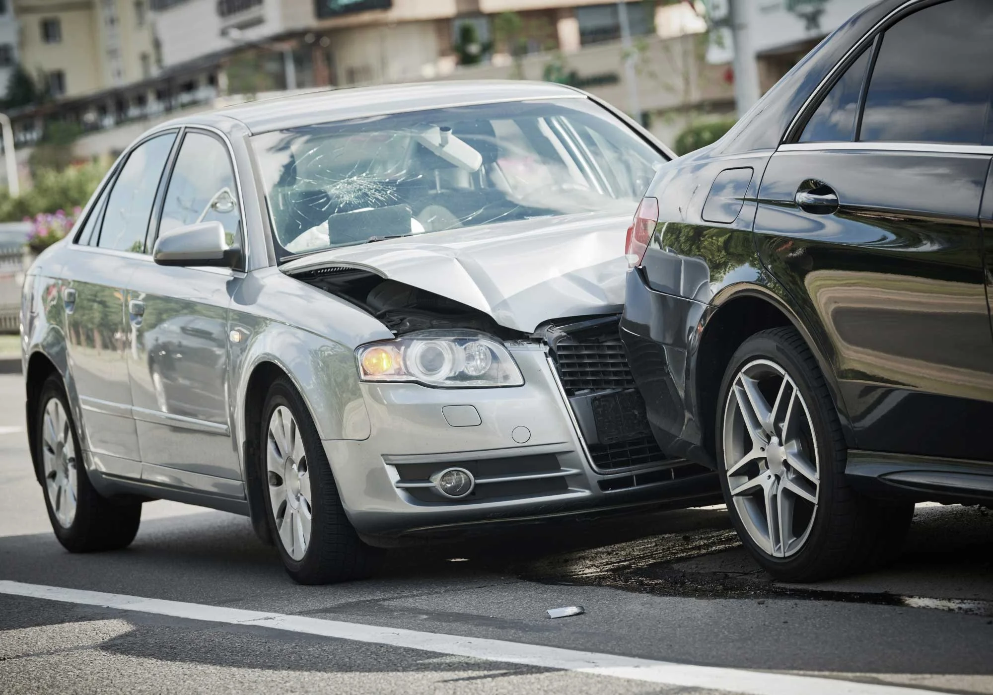 A silver audi that rear ended a black sedan