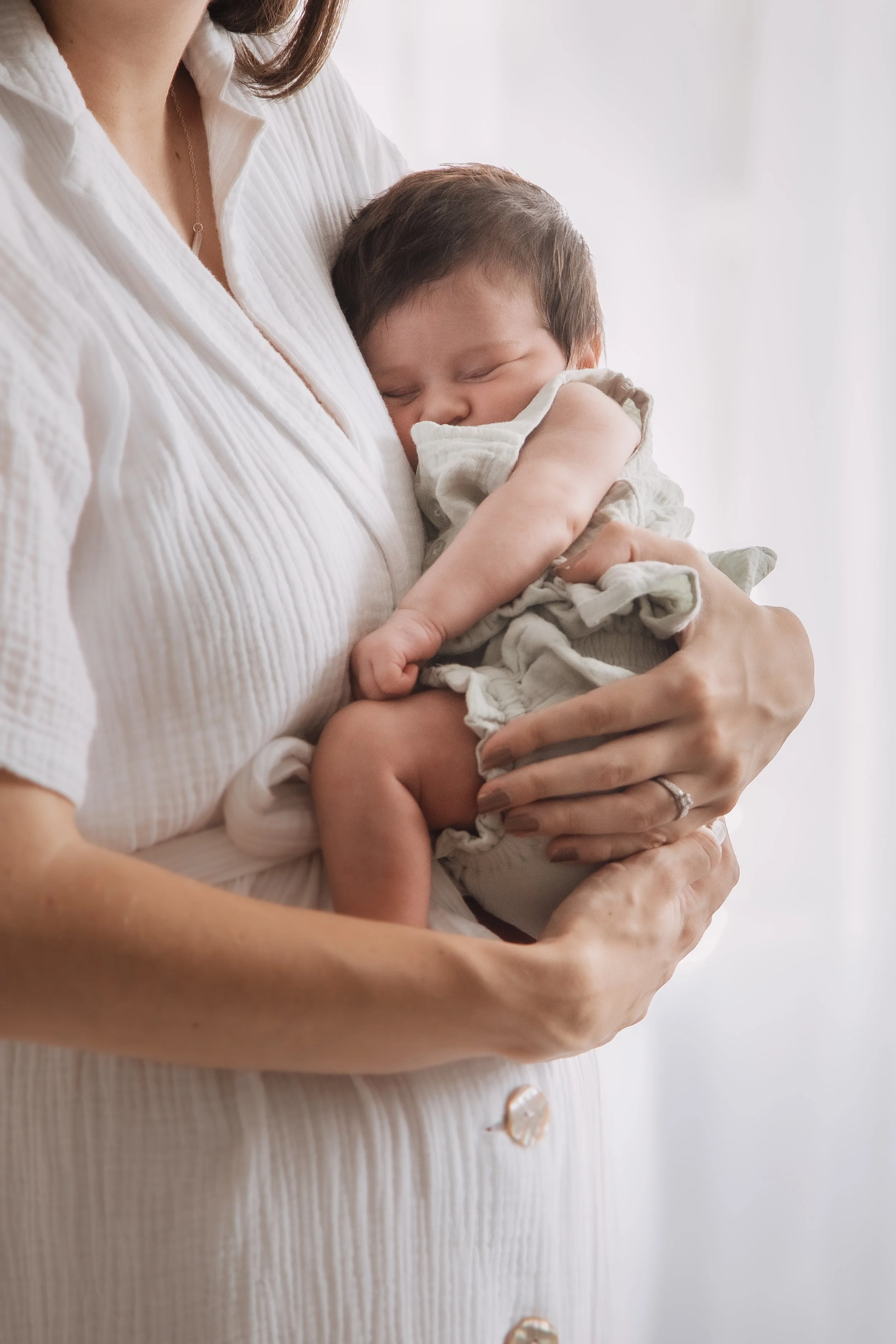 A woman holding a sleeping baby in her arms.