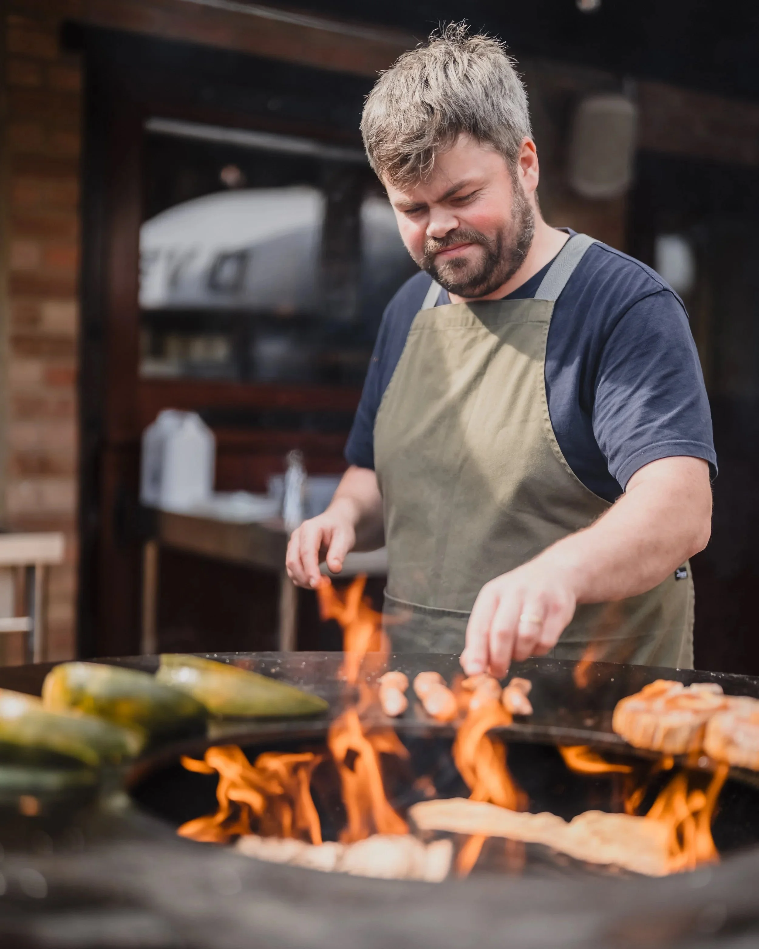 Man cooking food on a flaming outdoor grill