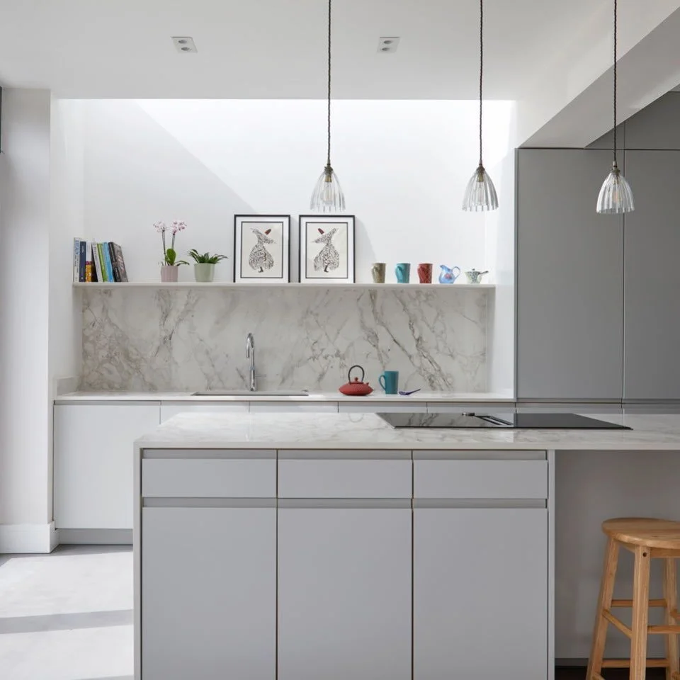 Our member @lumin.architects is an award-wining architectural designer 
🏡 
Grey cabinetry, marble worktop and splashback, pendant lights that drop from a rooflight slot above. The shelf keeps things personal without cluttering the surfaces below. 
?