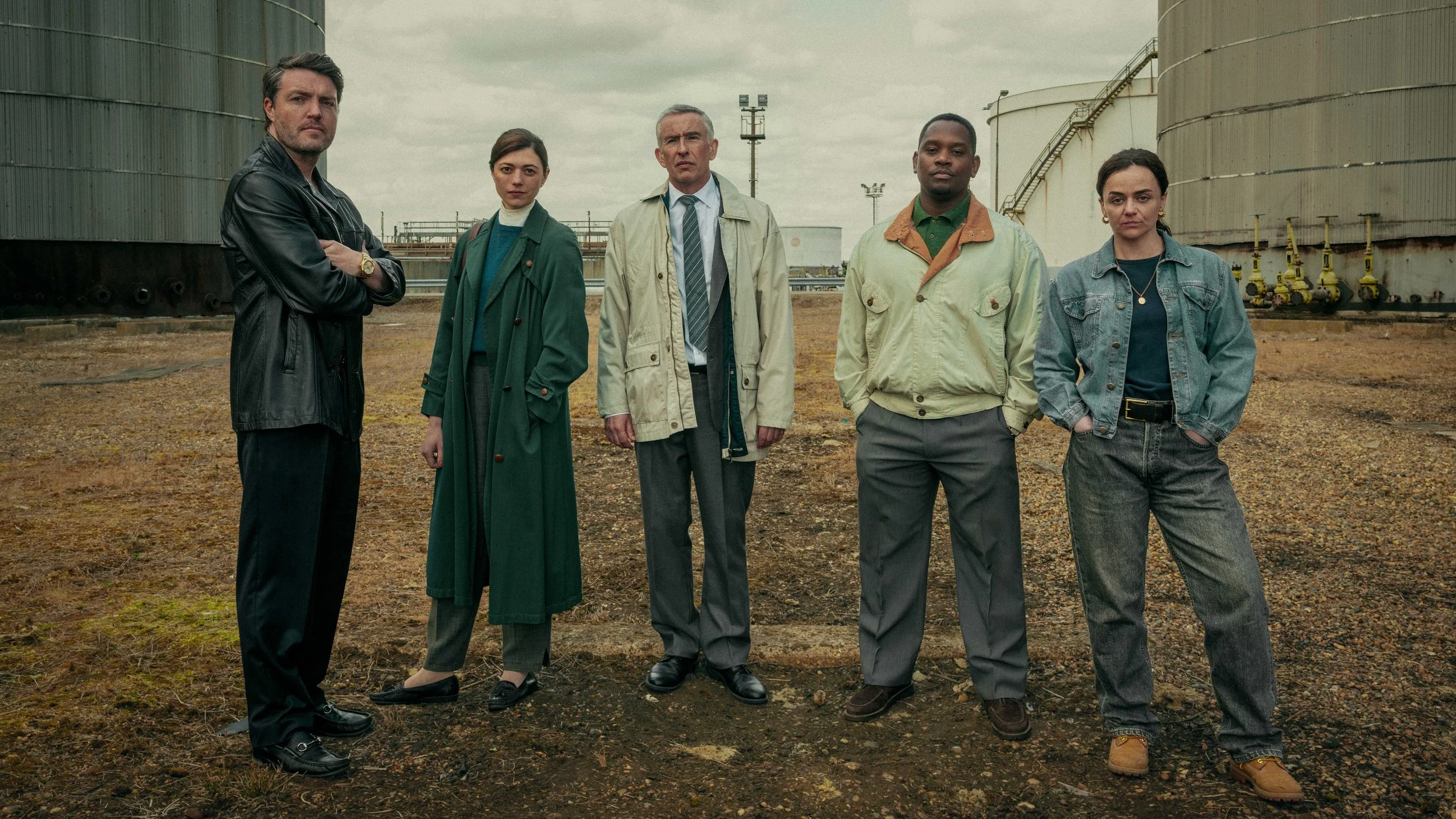Cast photo for Legends, Netflix written by Neil Forsythe,  Tom Burke, Jasmine Blackborow, Steve Coogan, Aml Ameen, Hayley Squires. The cast stand in a desolate wasteland facing the camera. Photo by Sally Mais

