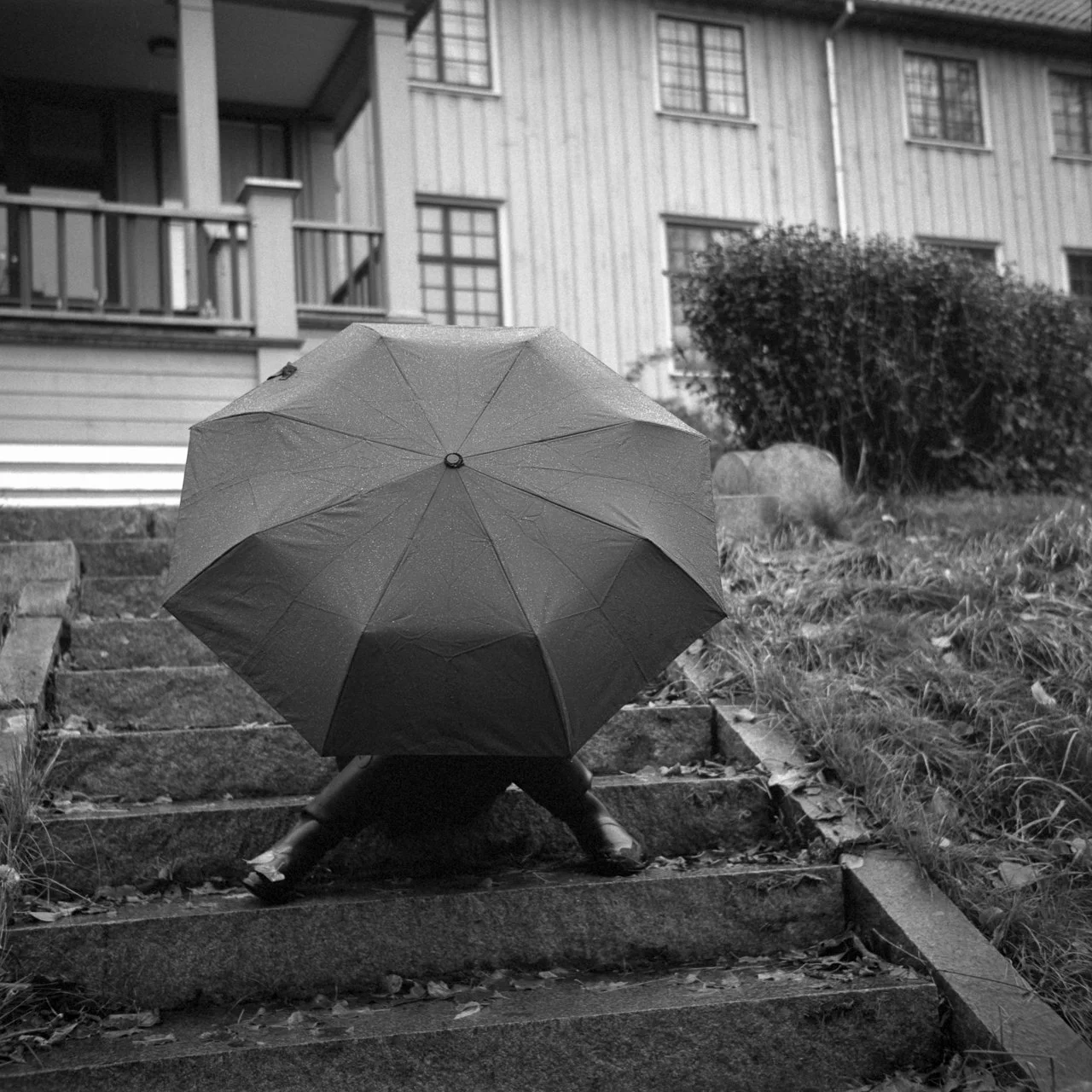 Elisabeth sitting in the stairs at Elingaard in Fredrikstad with an umbrella