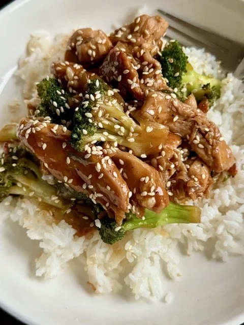 Chicken & Broccoli Stir Fry in a white bowl with flavorful sauce and colorful vegetables
