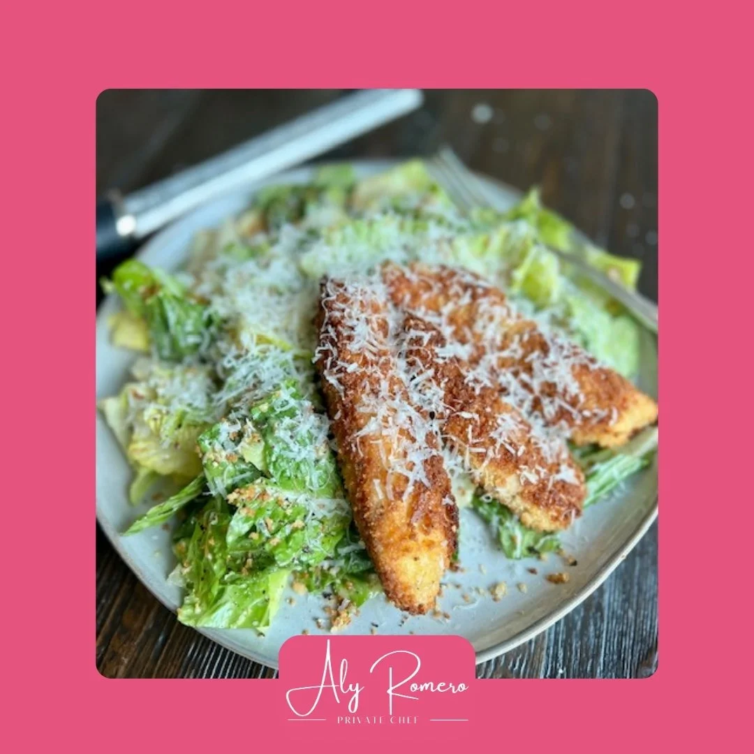 Salad with breaded chicken tenders topped with shredded cheese on a white plate