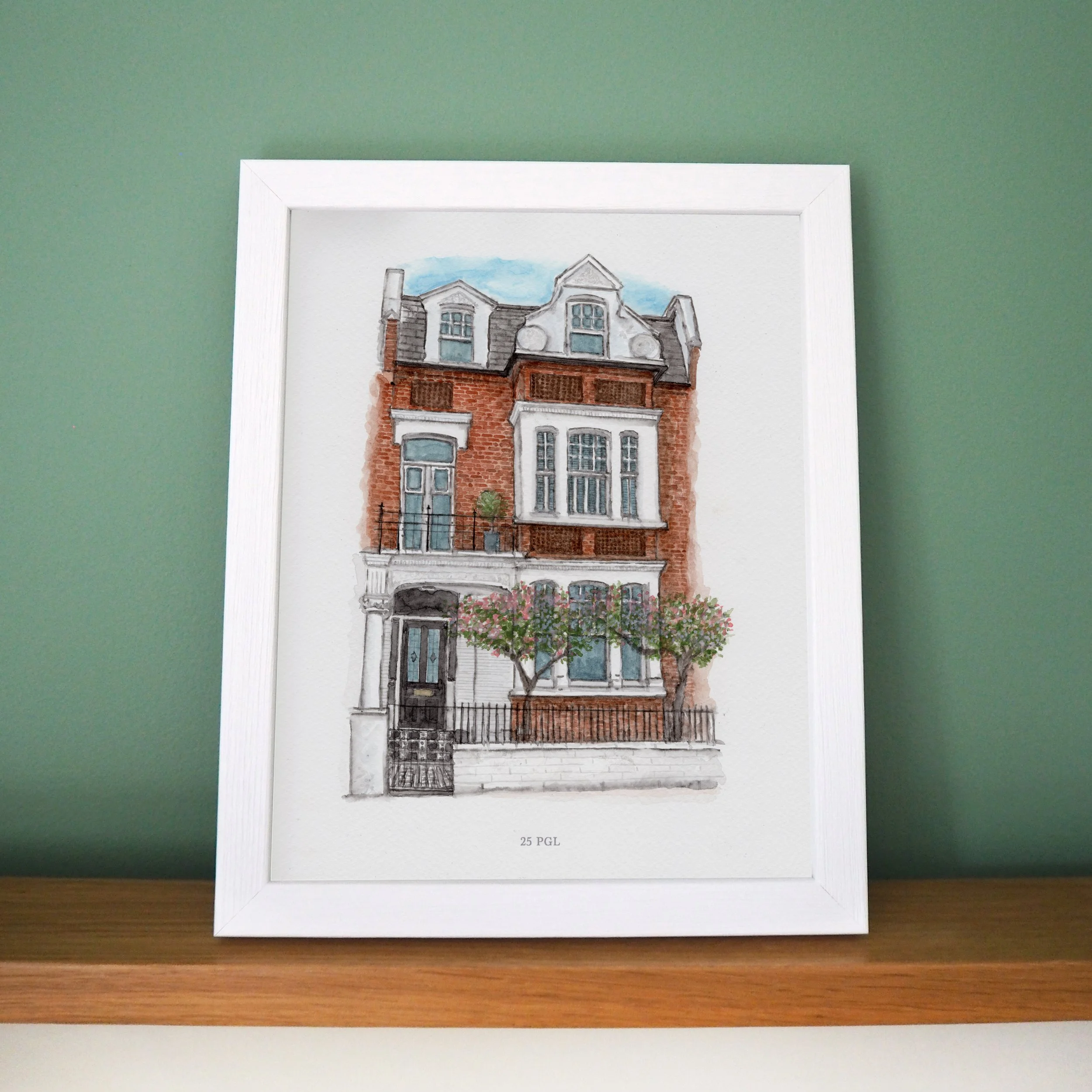 A framed watercolour painting of a london townhouse with a black door