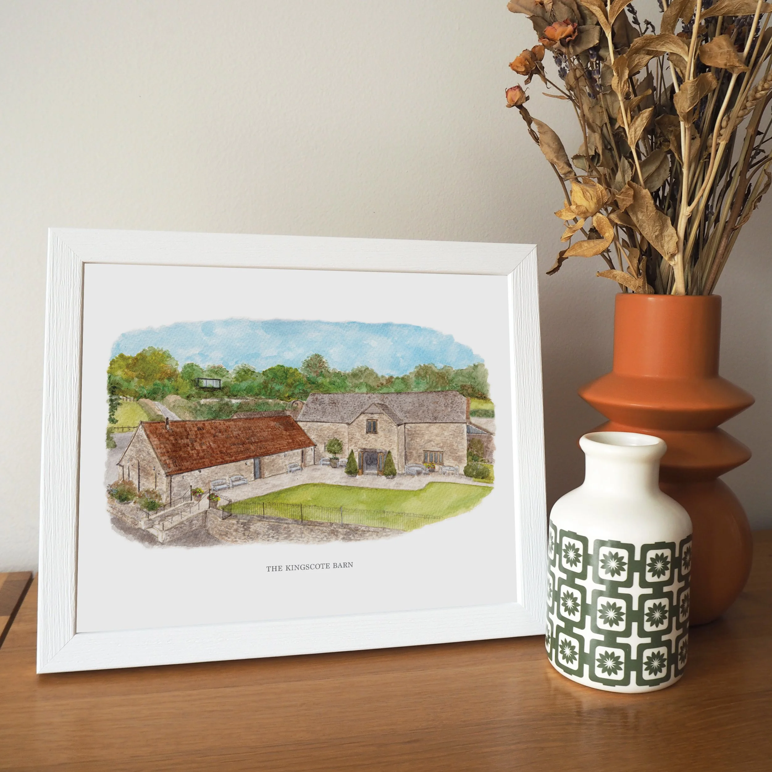 A framed personalised print of a watercolour illustration of wedding venue The Kingscote Barn
