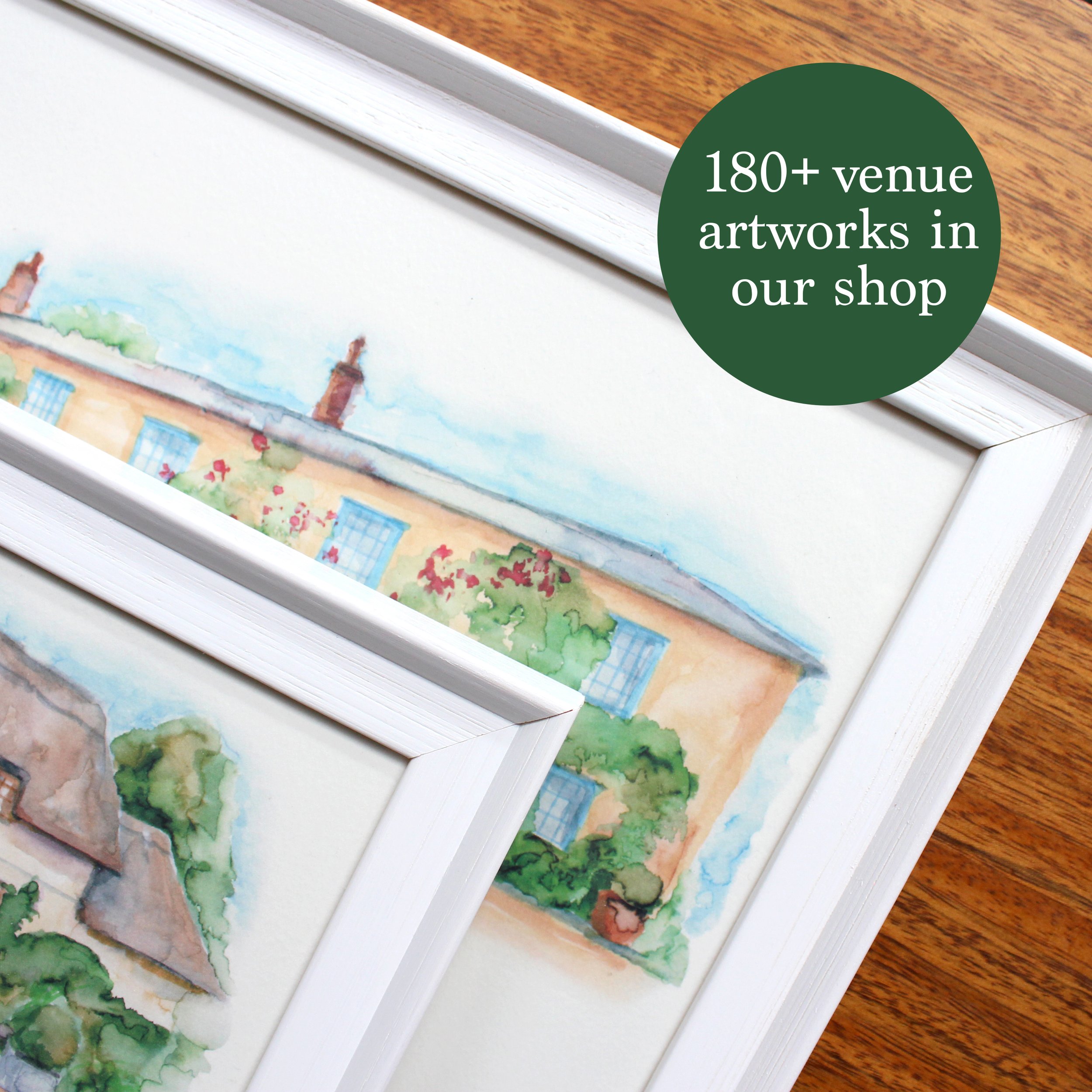 2 white wooden frames sat on a wooden surface, with watercolour paintings inside
