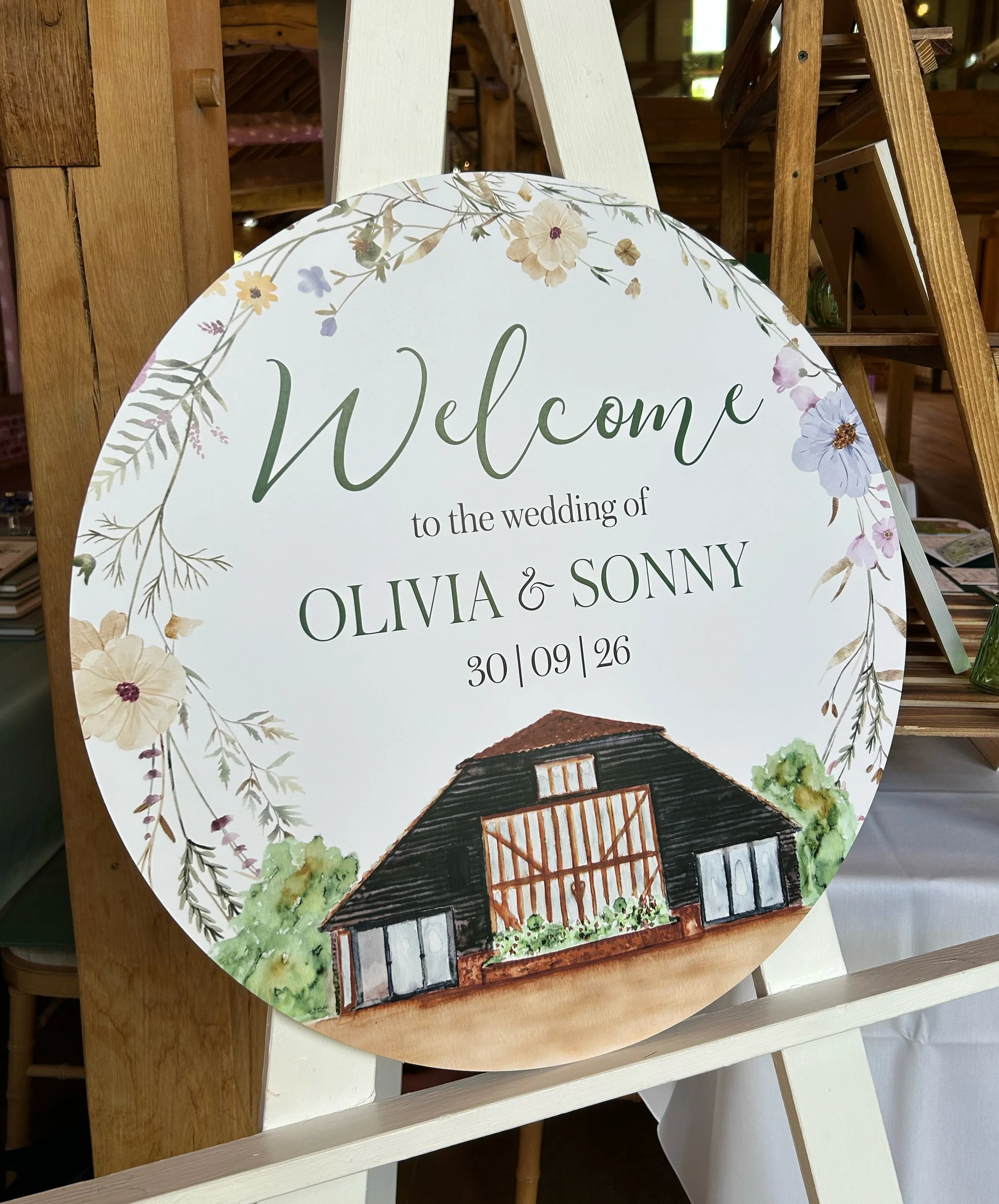 A round wedding welcome sign featuring a watercolour illustration of Blake Hall