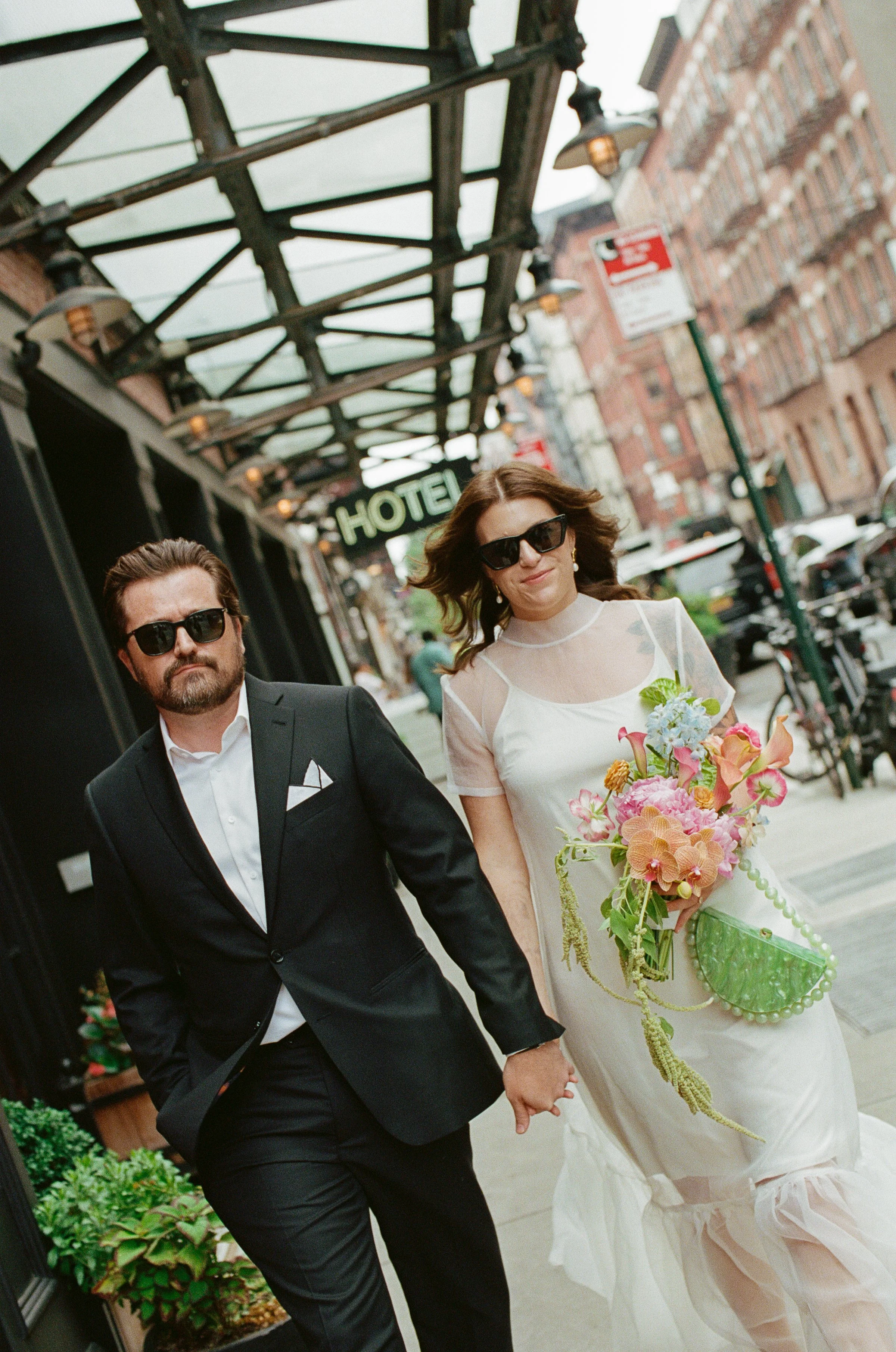 Cool fashionable couple walking in NYC with modern wedding bouquet