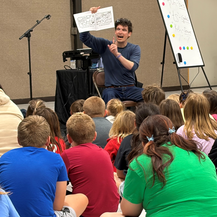 Description: Skippy reads his children’s book “Boots, Andy, Cats: a world for all ages, shapes, and sizes” for an indoor field trip in Carlisle, Iowa. (2026)