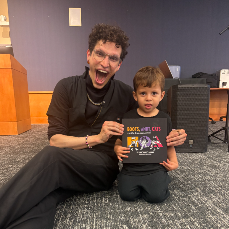 Photo: Skippy with Ari from Iowa City Public Library. His grandma purchased a copy of Skippy’s children’s book “Boots, Andy, Cats: a world for all ages, shapes, and sizes,” reviewing the book as “positive” and “full of inclusive messaging.' (2026)