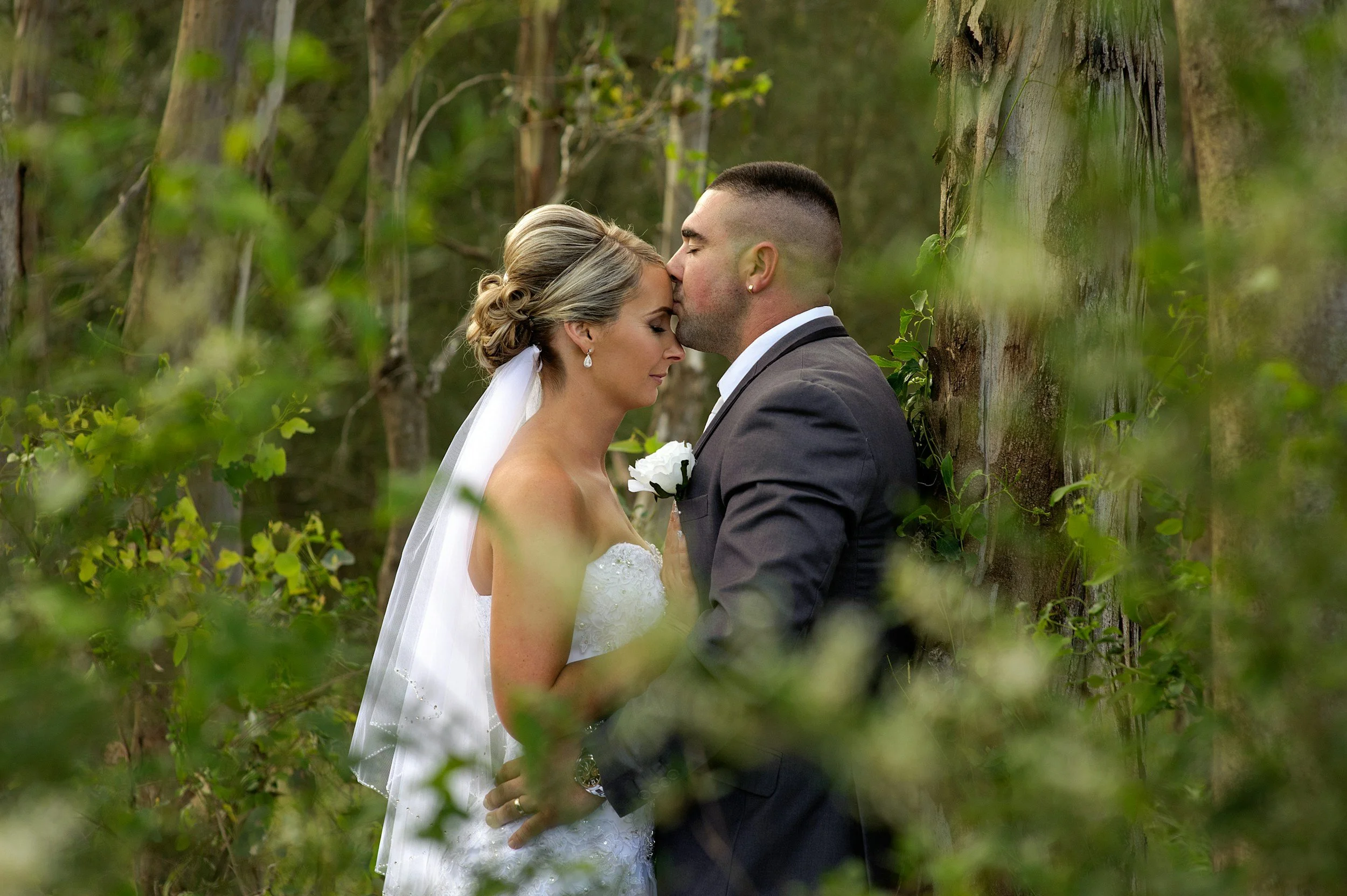 Bride and groom embracing in forest setting, wedding photo