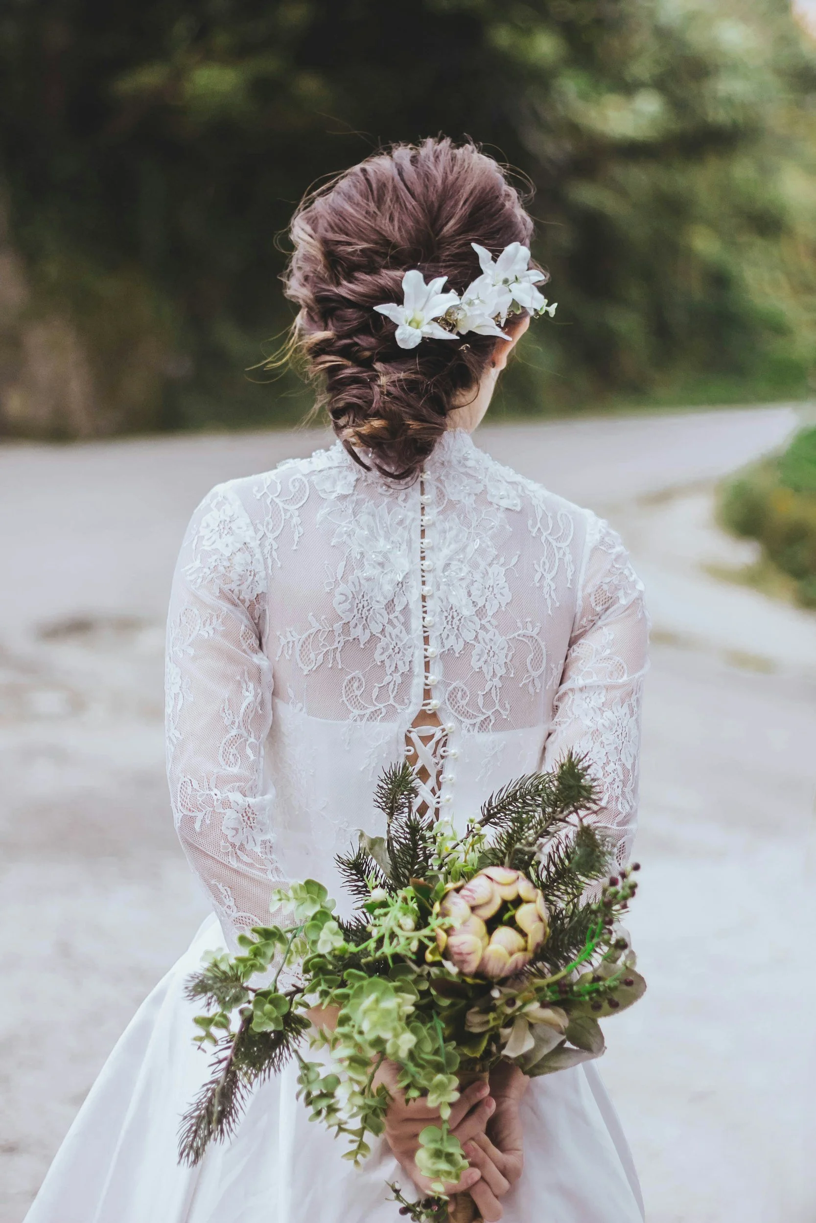 Bride in lace dress holding bouquet, back view