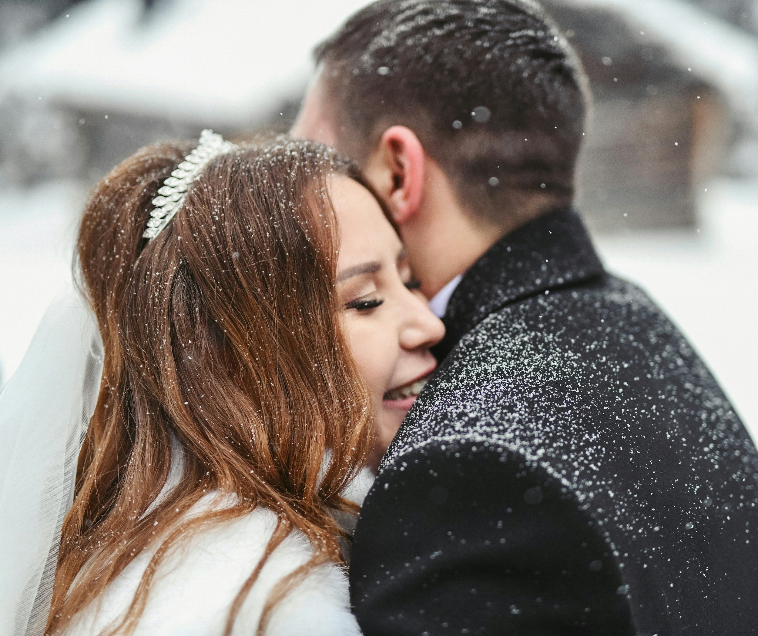 Bride and groom embracing in snowy winter setting.
