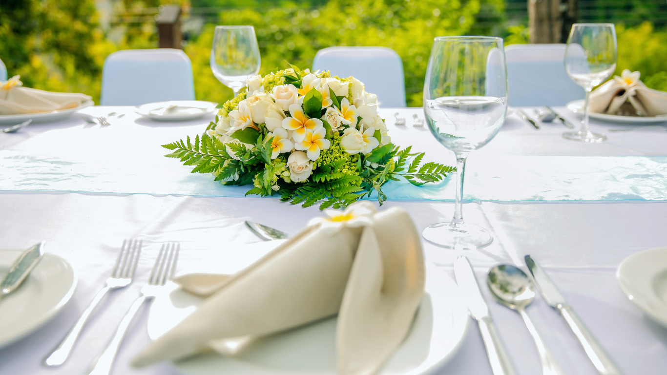 Elegant table setup with floral centerpiece, white napkins, silverware, and wine glasses