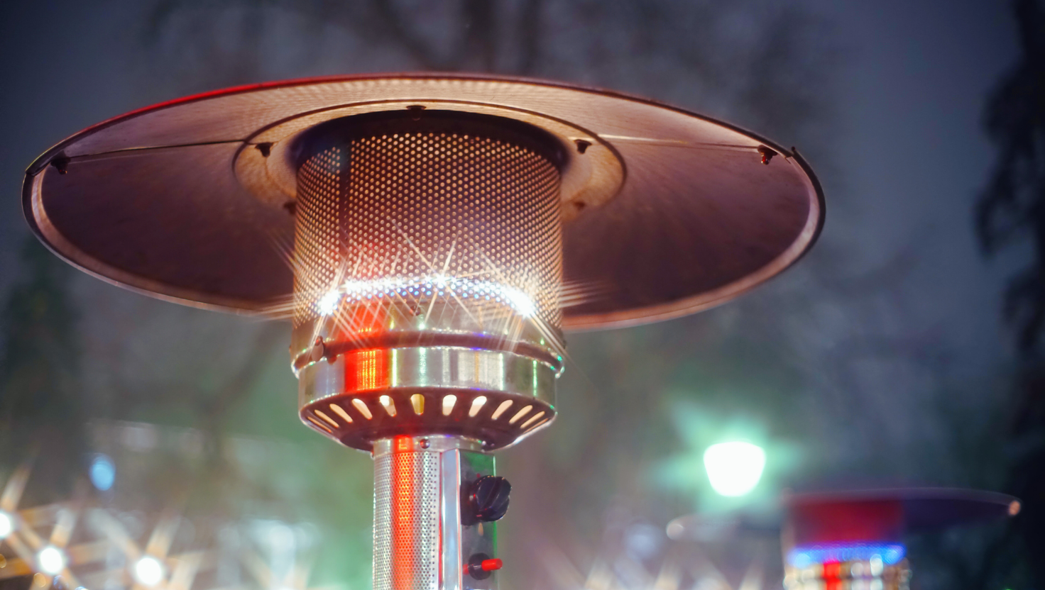 Outdoor gas patio heater with glowing light, night view.