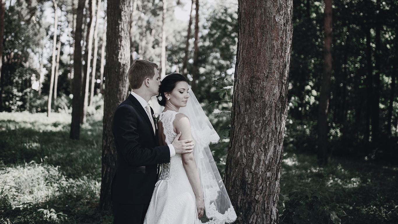Bride and groom posing in forest, wedding attire