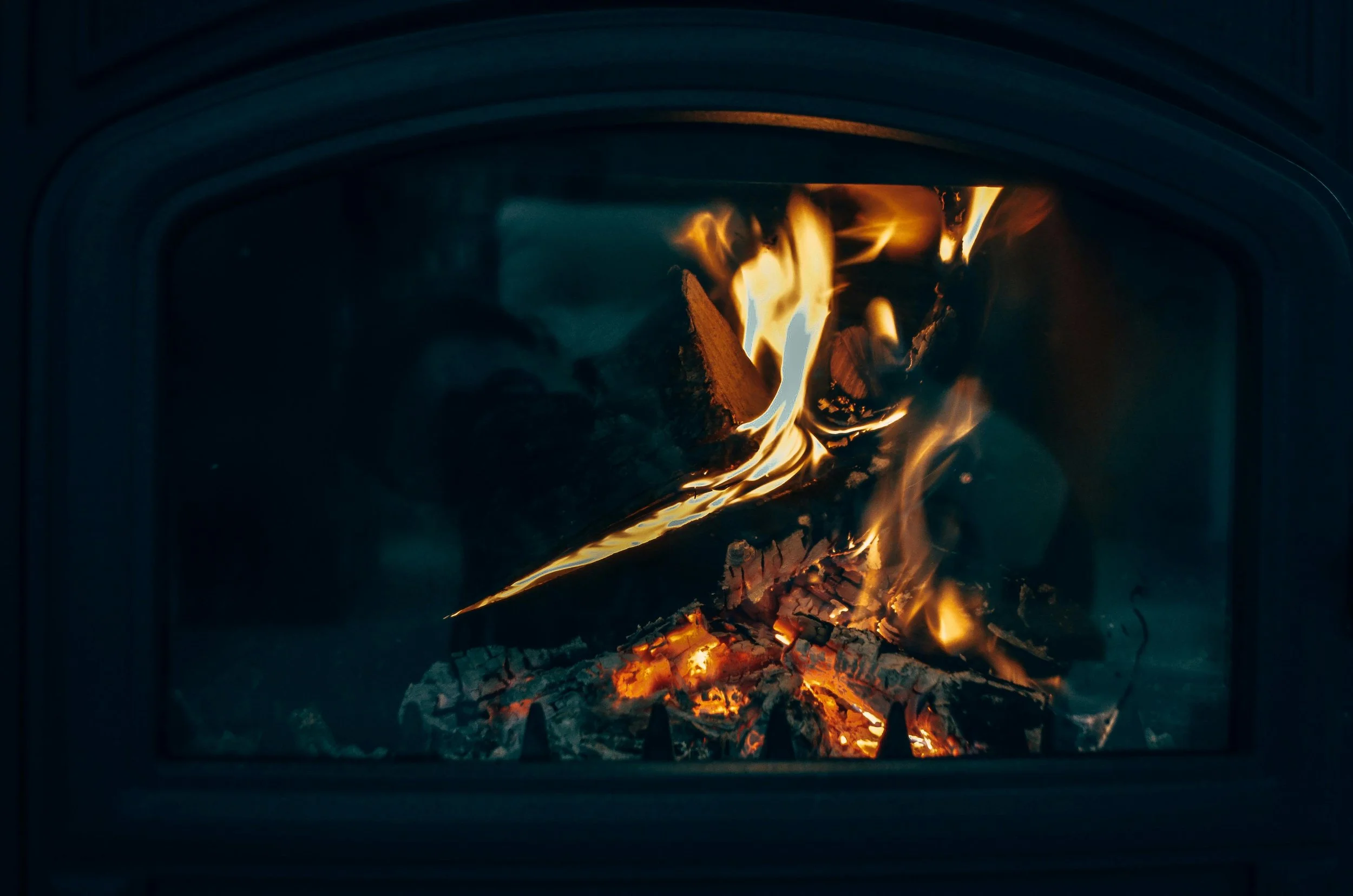 a dark grey hearth fire with glowing orange flames traveling up the forward most logs