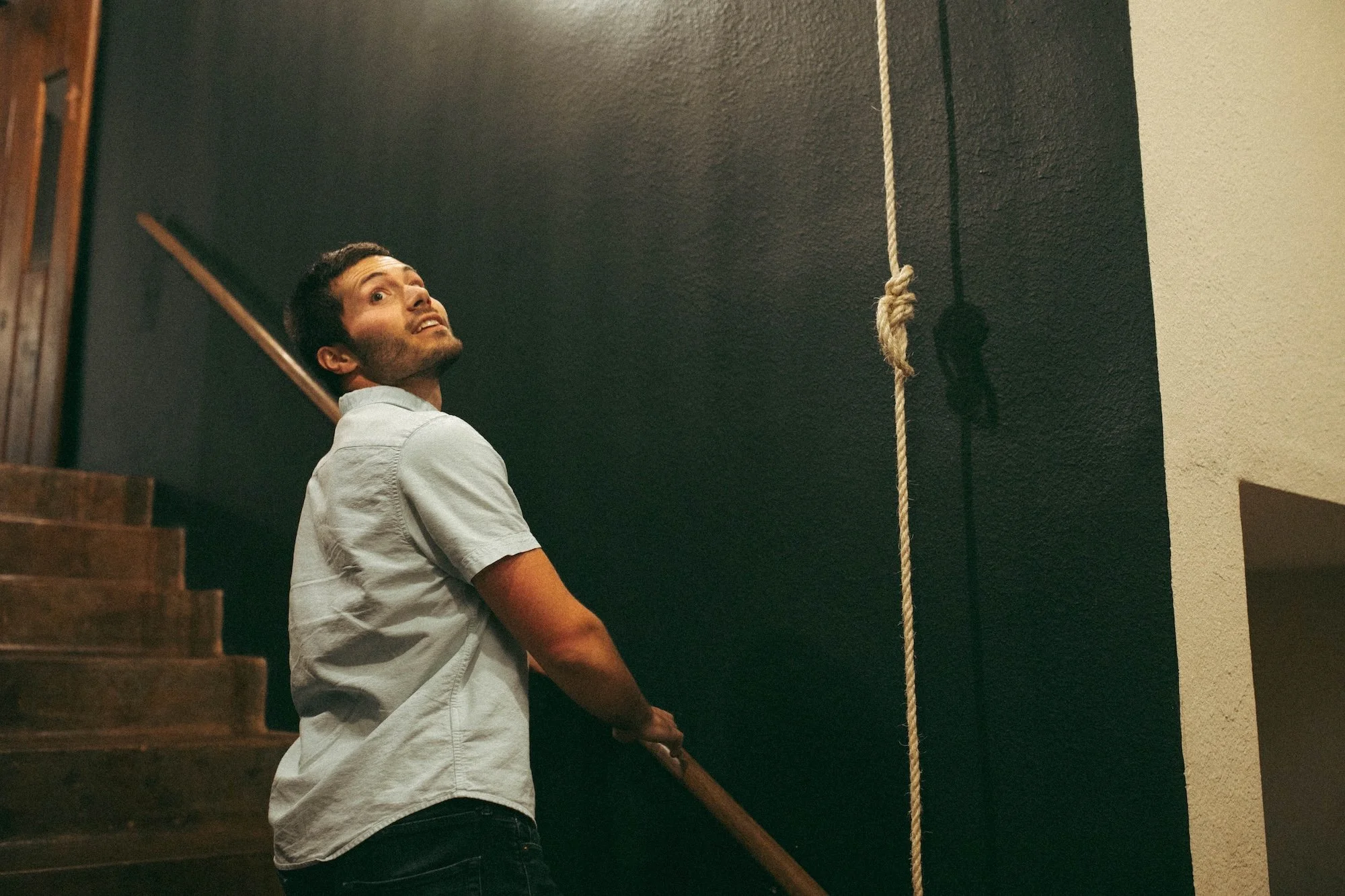 A Gilliam faculty member on a staircase glancing up at a hanging bell rope.