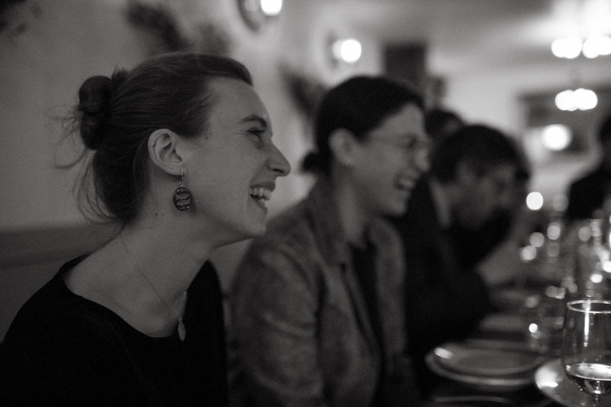 A colleague laughing warmly among friends at the dinner table.