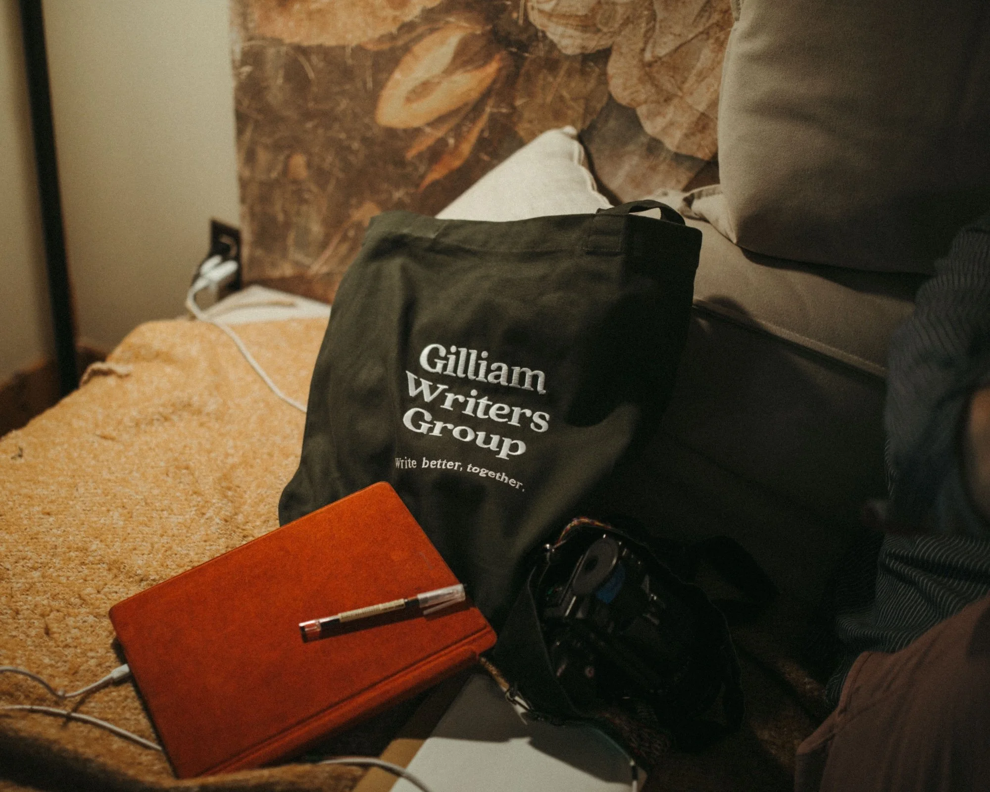 A Gilliam Writers Group tote and notebook resting on a couch.