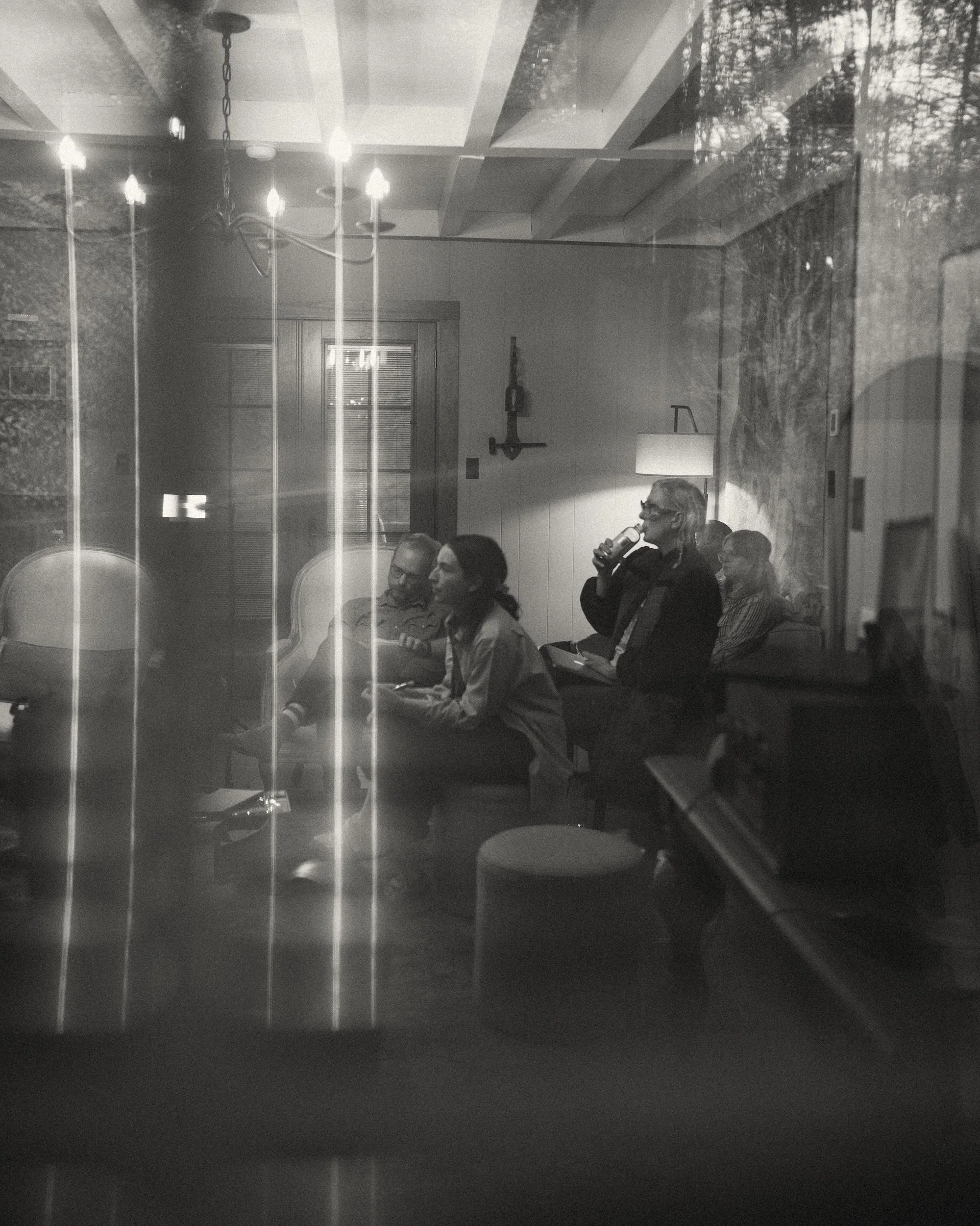 Gilliam Writers Group faculty gathered for an evening retreat session, seen through a window.