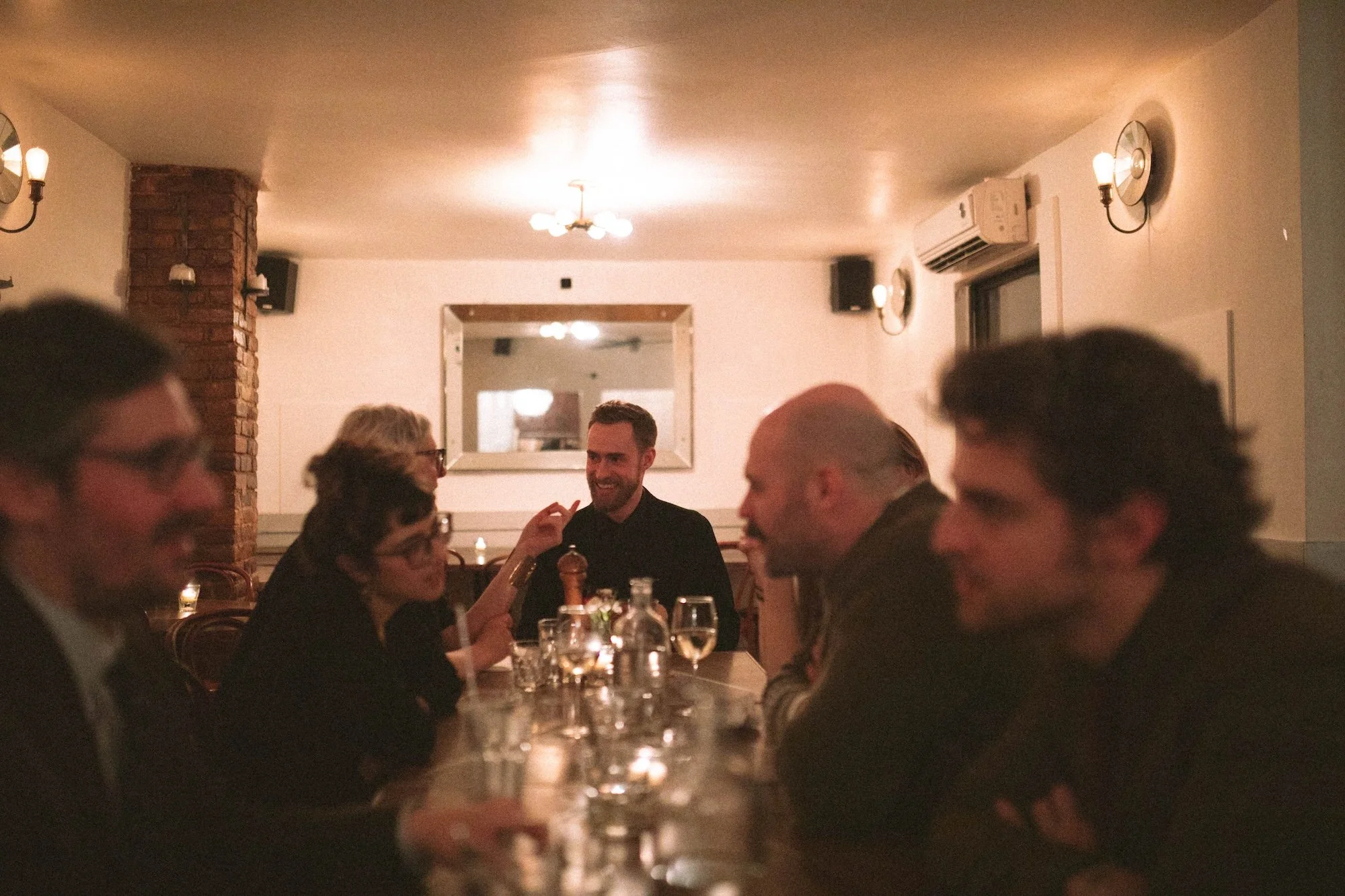 Brady Gilliam and Gilliam Writers Group faculty in warm conversation around a candlelit dinner table.