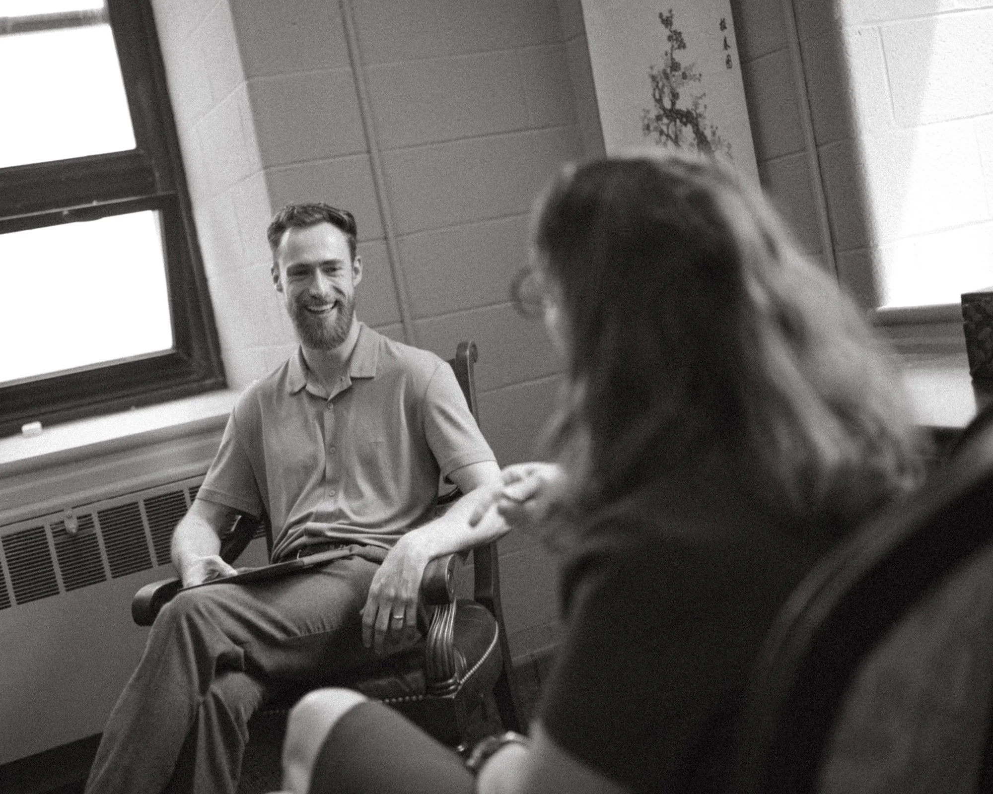 Brady Gilliam laughs by a bright office window during an interview with a college professor.