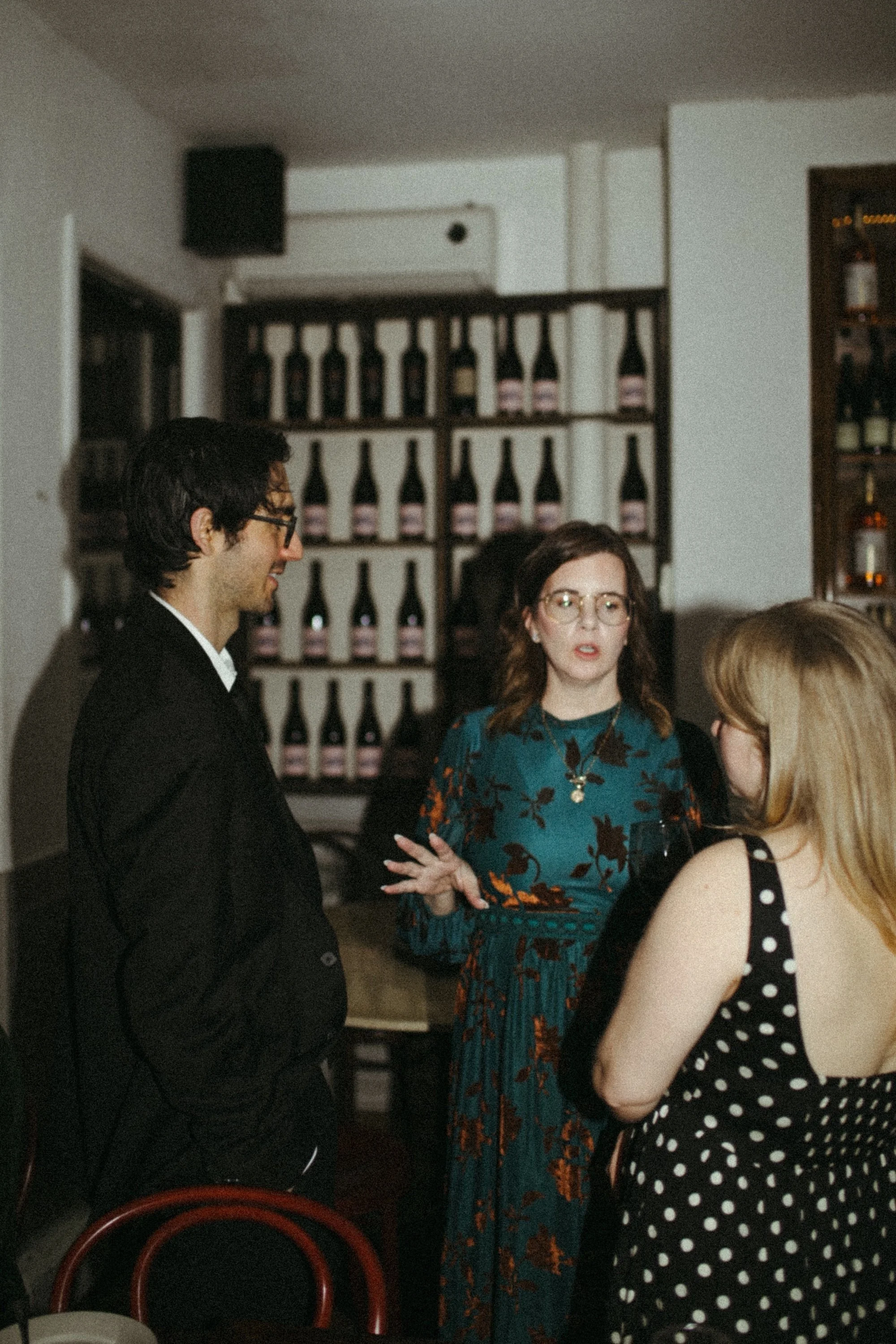 Three Gilliam Writers Group colleagues in animated conversation at a wine-bar gathering.