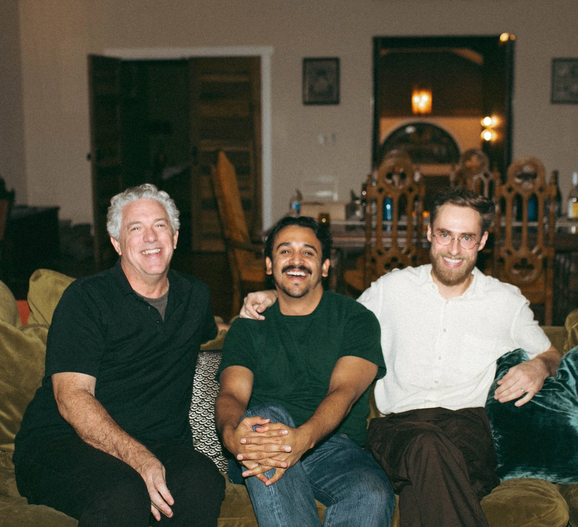 Three GWG faculty members smiling side by side on a couch.