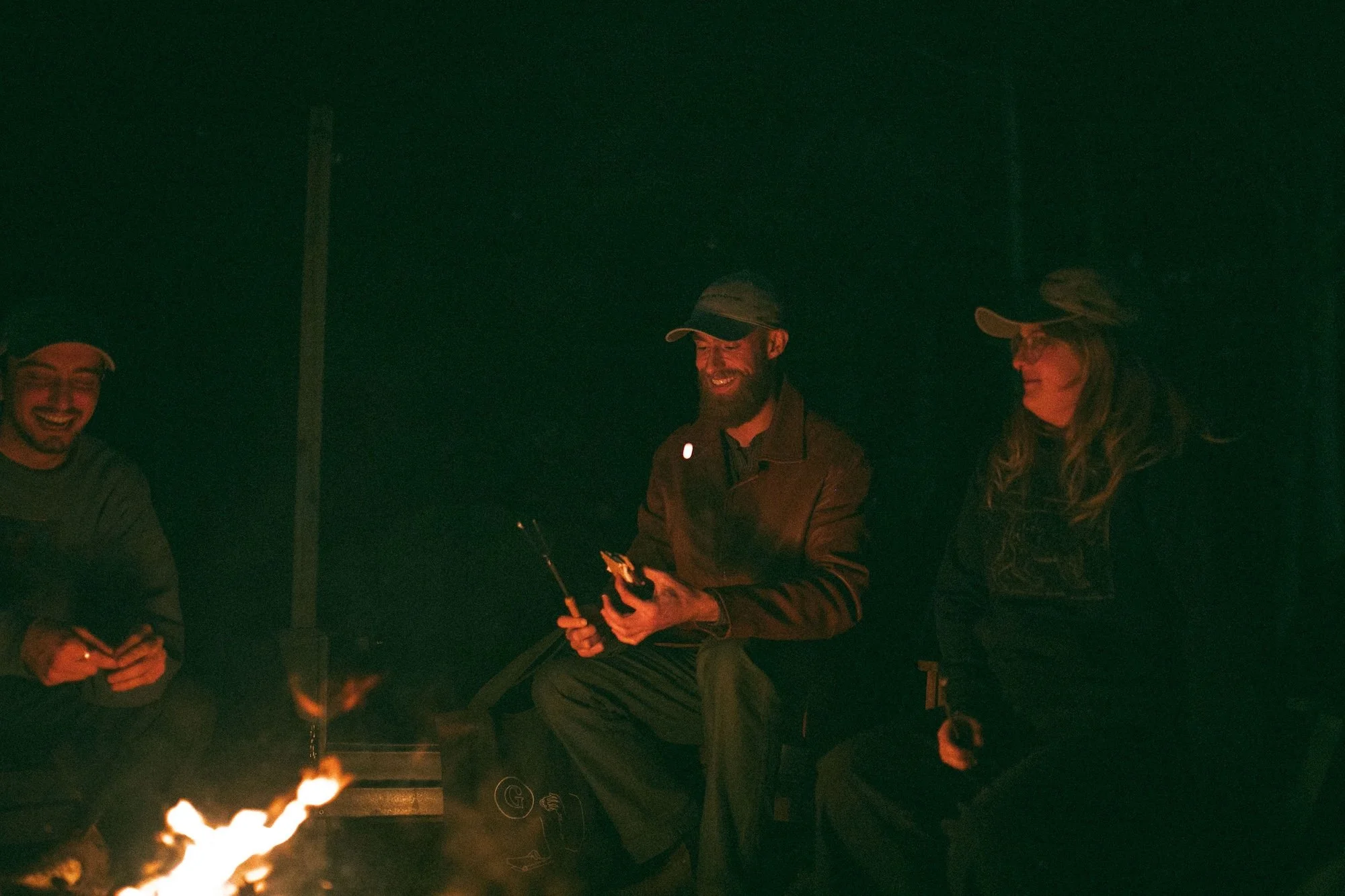 Gilliam Writers Group colleagues sharing s'mores and laughter around a bonfire.