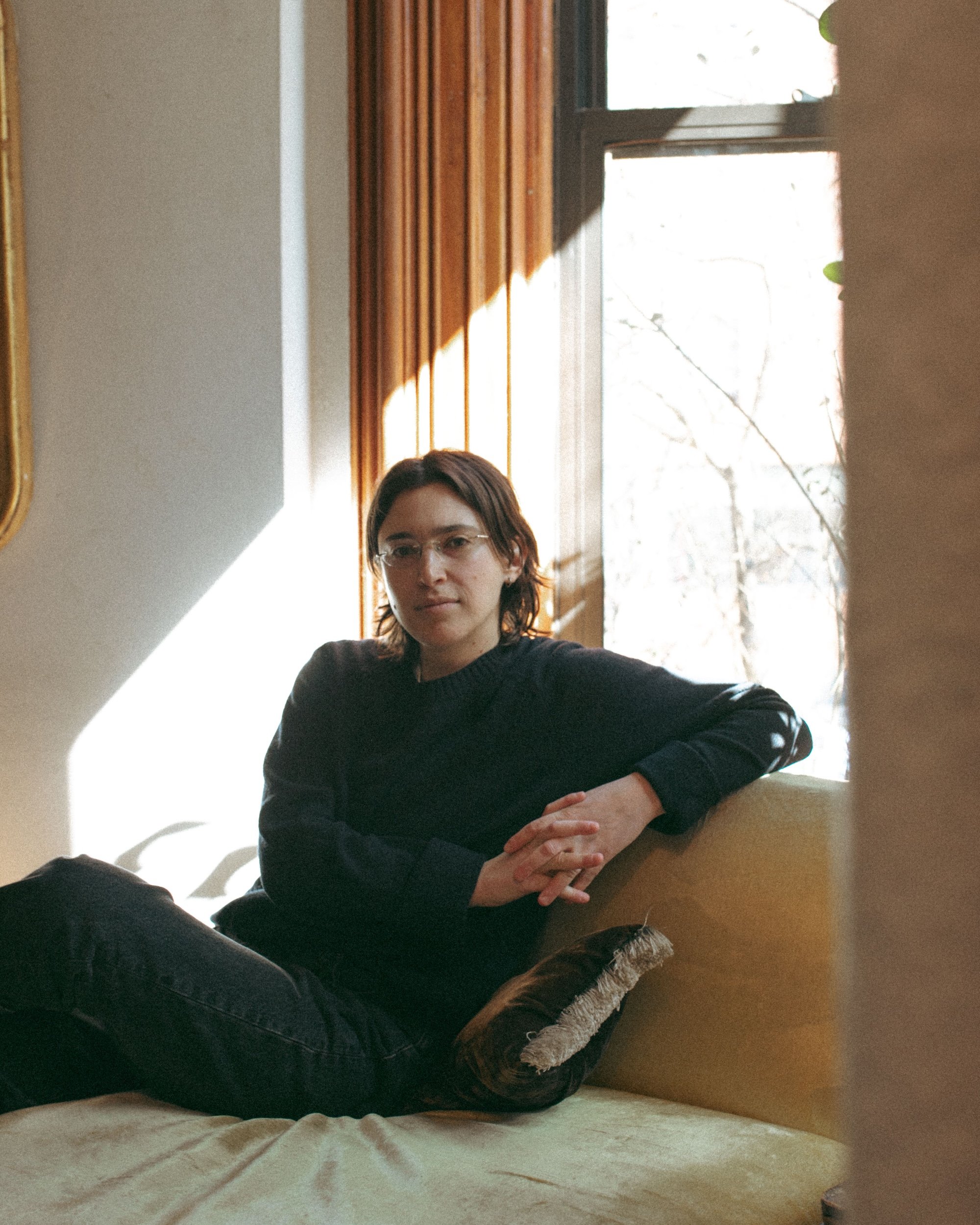 A relaxed faculty portrait beside a sunlit brownstone window.